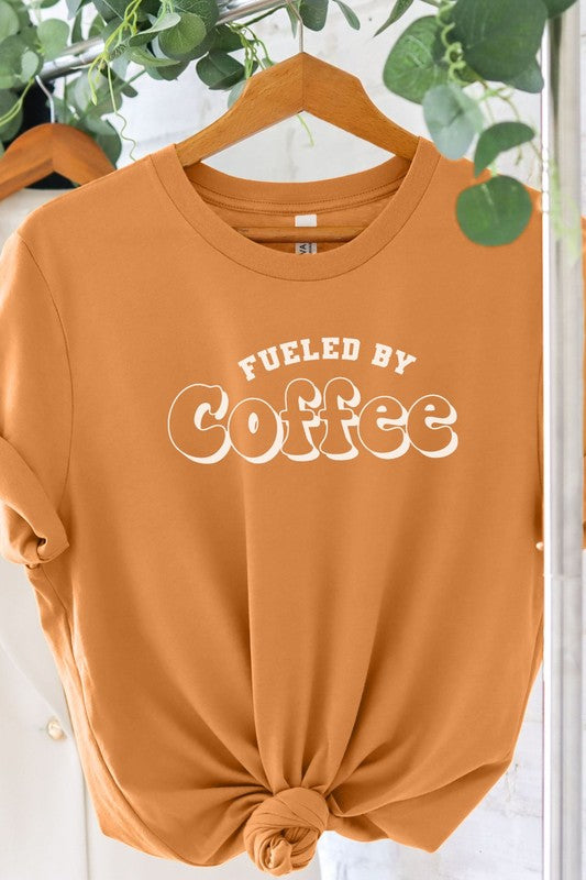 A stylish Fueled By Coffee Graphic Tee featuring a trendy coffee-themed design on a soft, lightweight fabric.