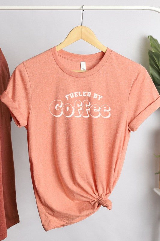 A stylish Fueled By Coffee Graphic Tee featuring a trendy coffee-themed design on a soft, lightweight fabric.