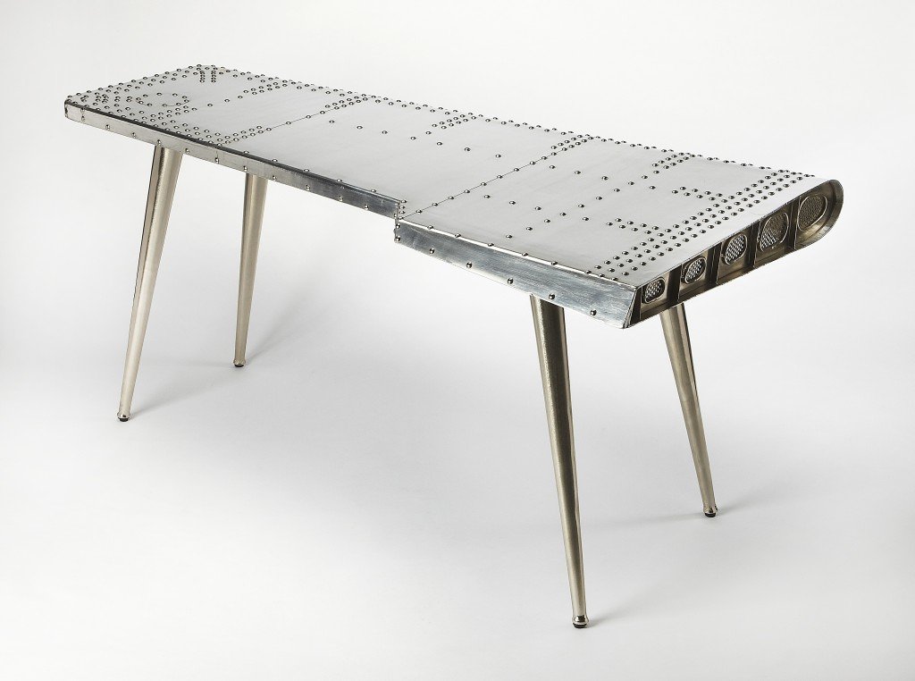 Funky Silver Wing Desk featuring a polished aluminum surface and tapered silver legs, designed to resemble an airplane wing.