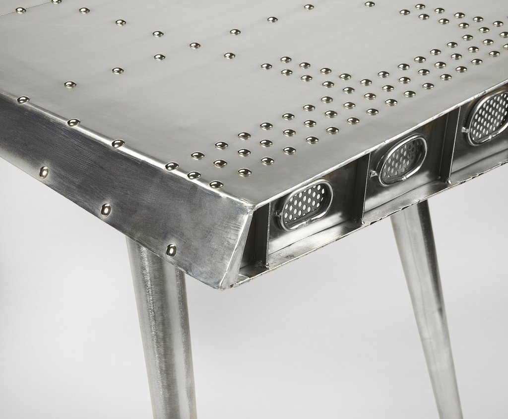 Funky Silver Wing Desk featuring a polished aluminum surface and tapered silver legs, designed to resemble an airplane wing.