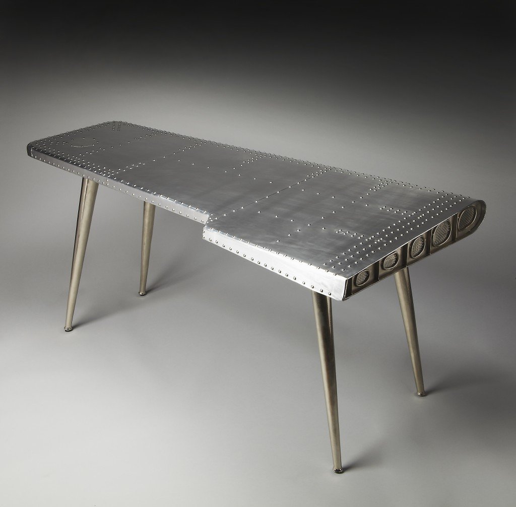 Funky Silver Wing Desk featuring a polished aluminum surface and tapered silver legs, designed to resemble an airplane wing.