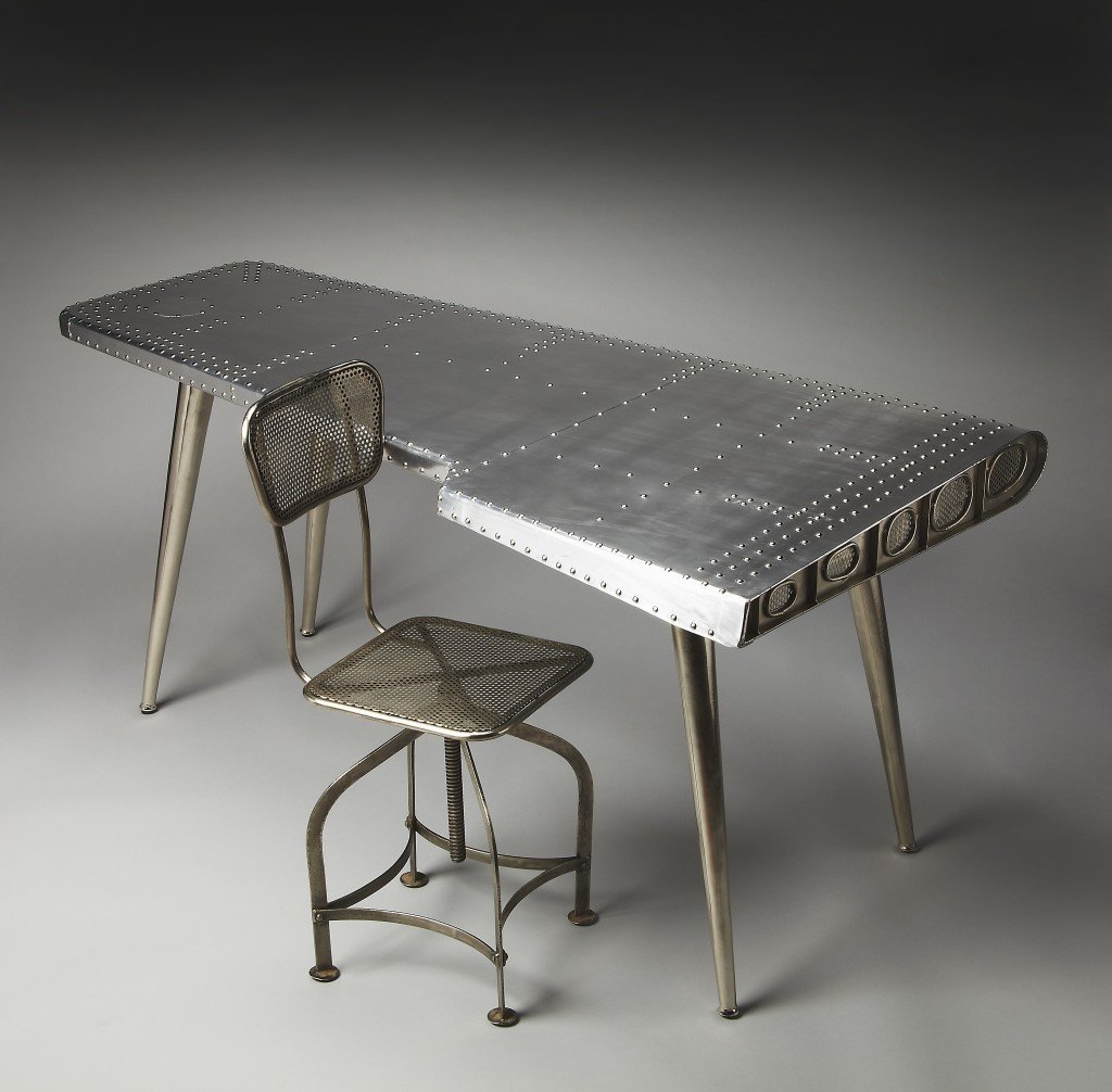 Funky Silver Wing Desk featuring a polished aluminum surface and tapered silver legs, designed to resemble an airplane wing.