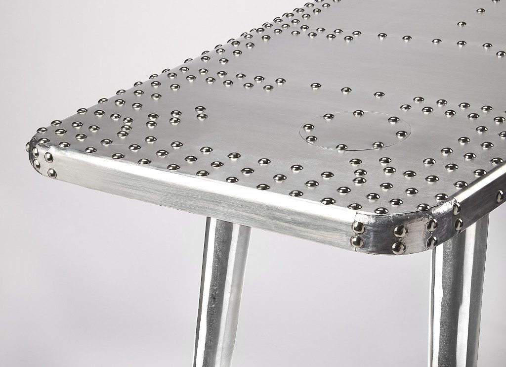 Funky Silver Wing Desk featuring a polished aluminum surface and tapered silver legs, designed to resemble an airplane wing.