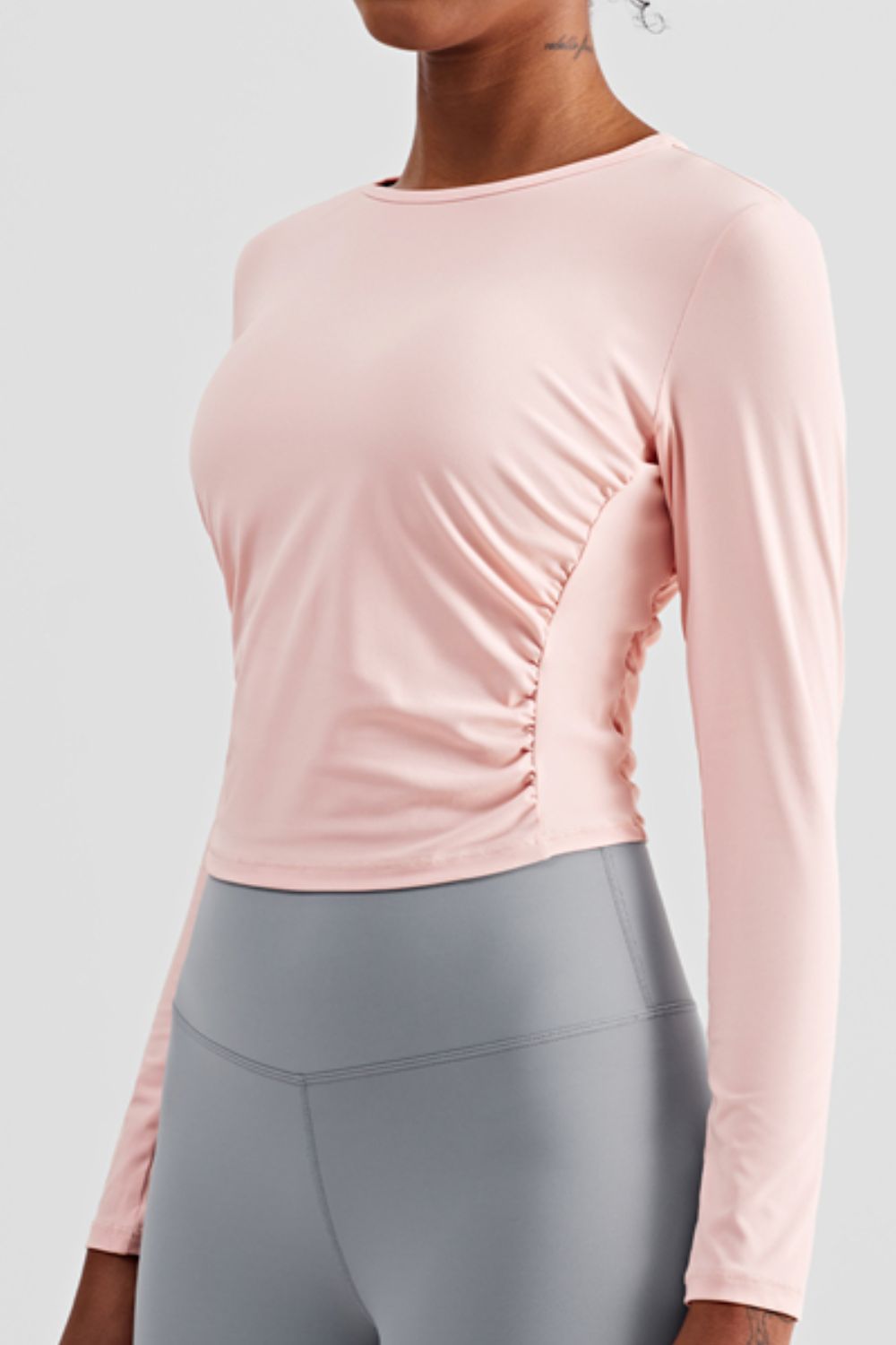 Gathered Detail Long Sleeve Sports Top in a studio setting, showcasing its solid pattern and comfortable fit.