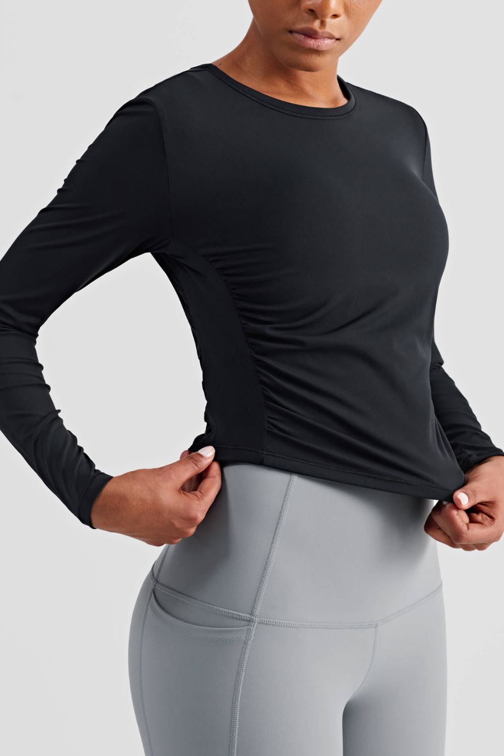 Gathered Detail Long Sleeve Sports Top in a studio setting, showcasing its solid pattern and comfortable fit.