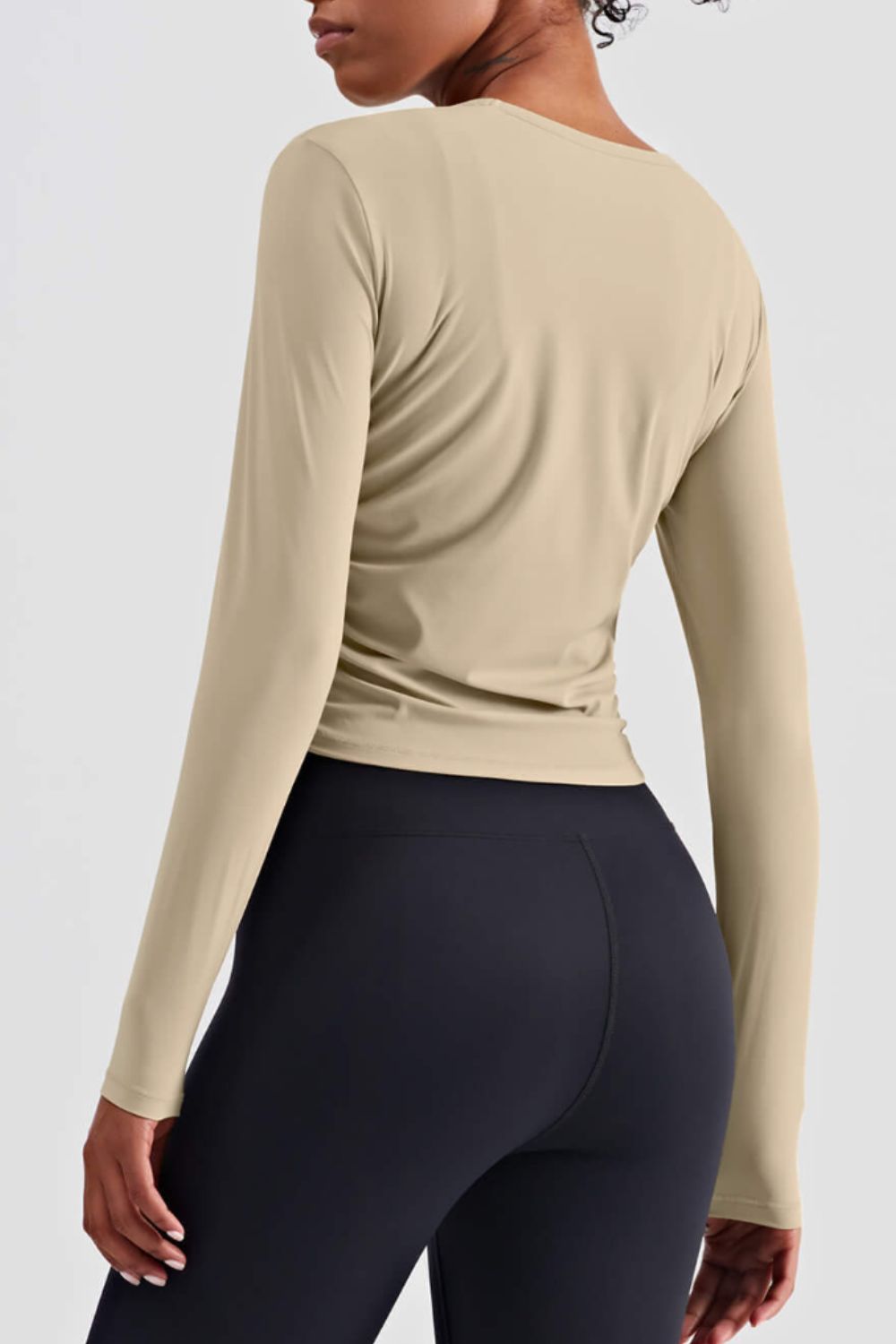 Gathered Detail Long Sleeve Sports Top in a studio setting, showcasing its solid pattern and comfortable fit.