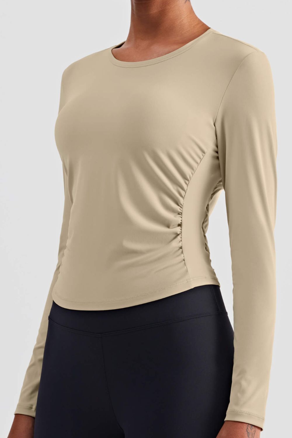 Gathered Detail Long Sleeve Sports Top in a studio setting, showcasing its solid pattern and comfortable fit.