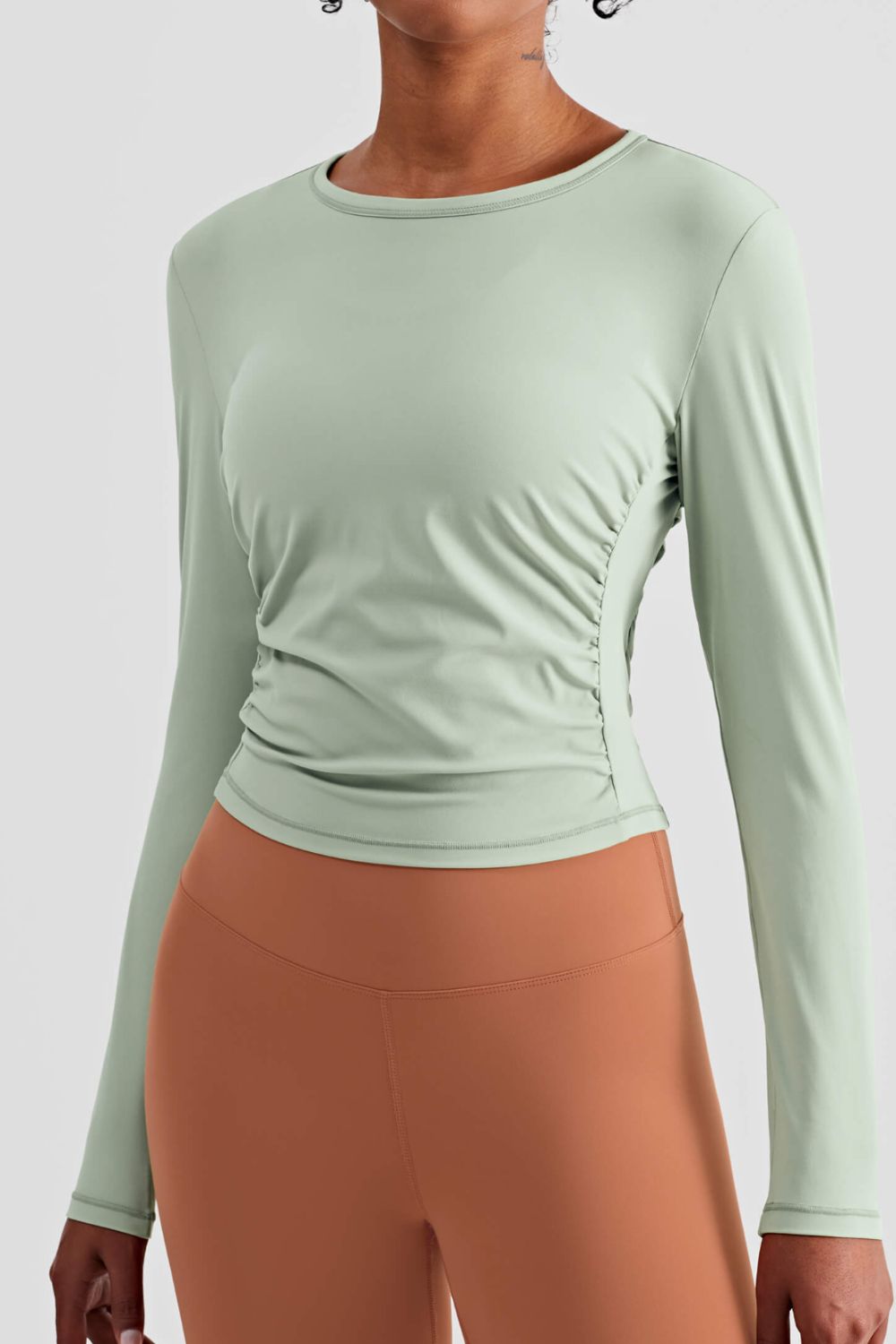 Gathered Detail Long Sleeve Sports Top in a studio setting, showcasing its solid pattern and comfortable fit.