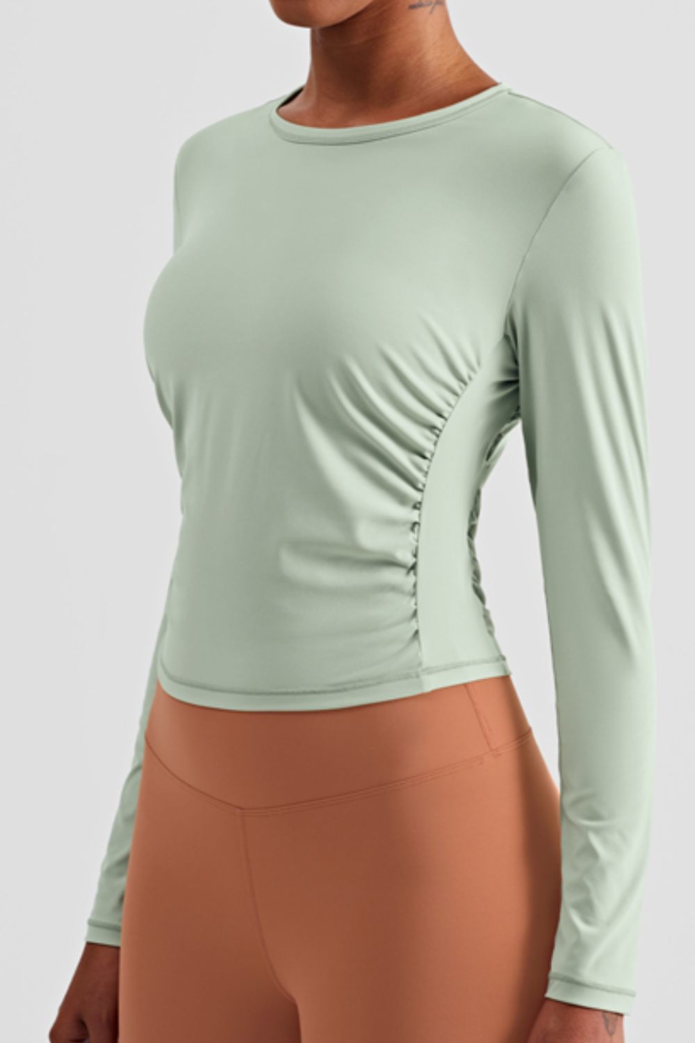 Gathered Detail Long Sleeve Sports Top in a studio setting, showcasing its solid pattern and comfortable fit.