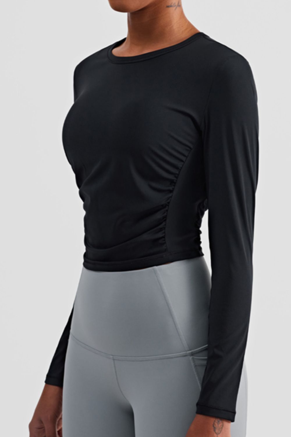 Gathered Detail Long Sleeve Sports Top in a studio setting, showcasing its solid pattern and comfortable fit.