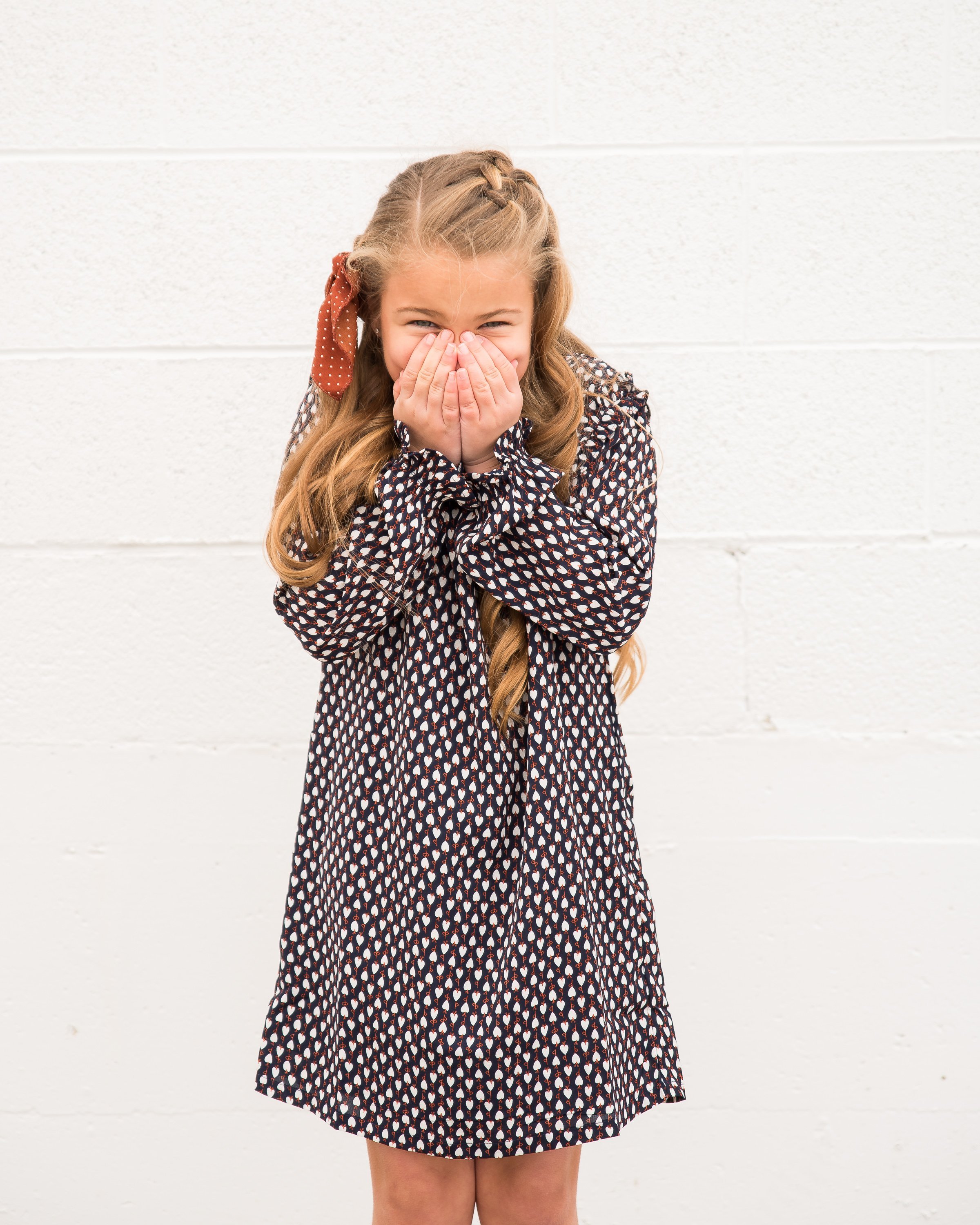 A cute navy geometric print shift dress for little girls featuring ruffle shoulders and long sleeves.