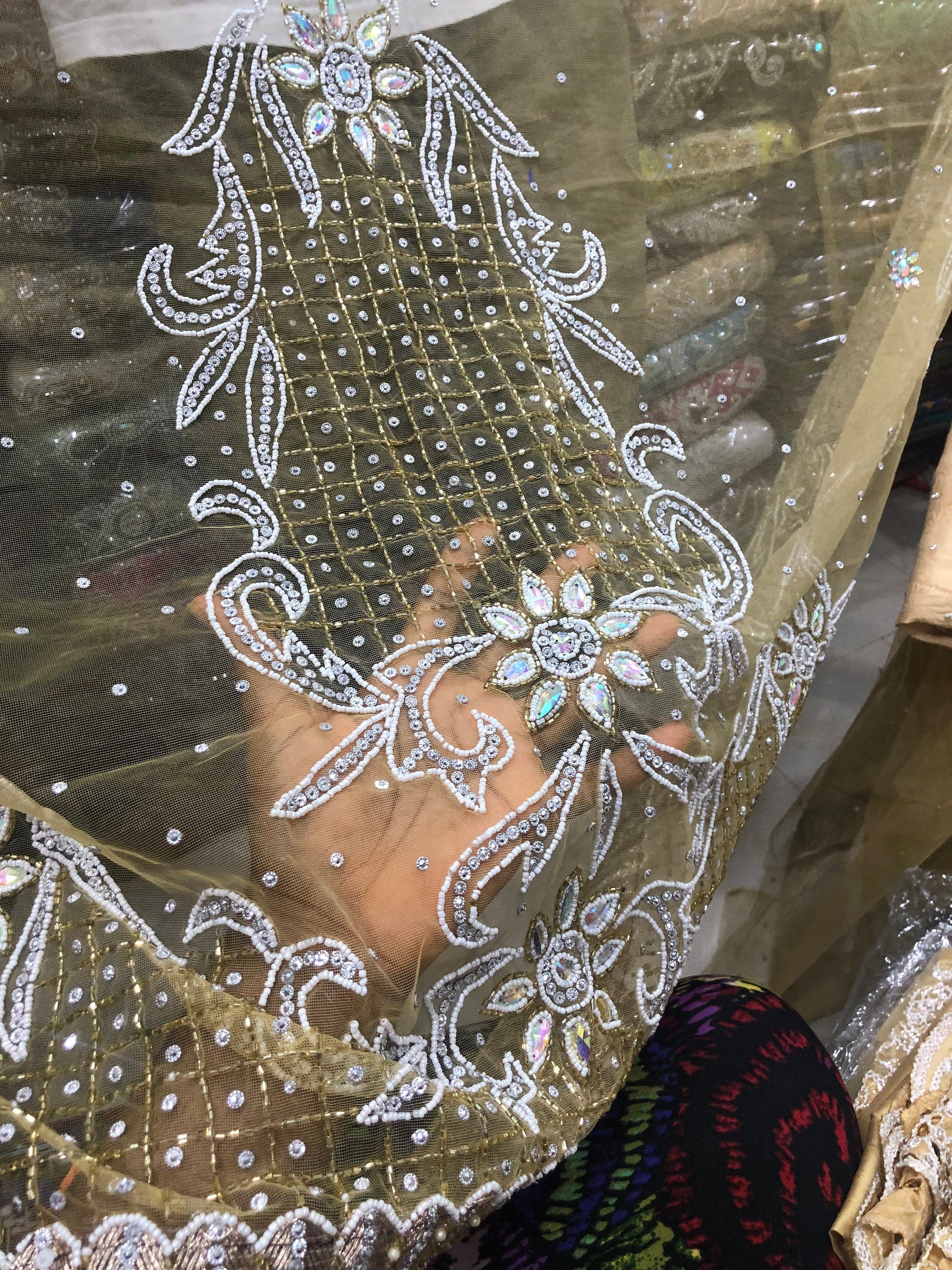 Hand holding intricate embroidered fabric.