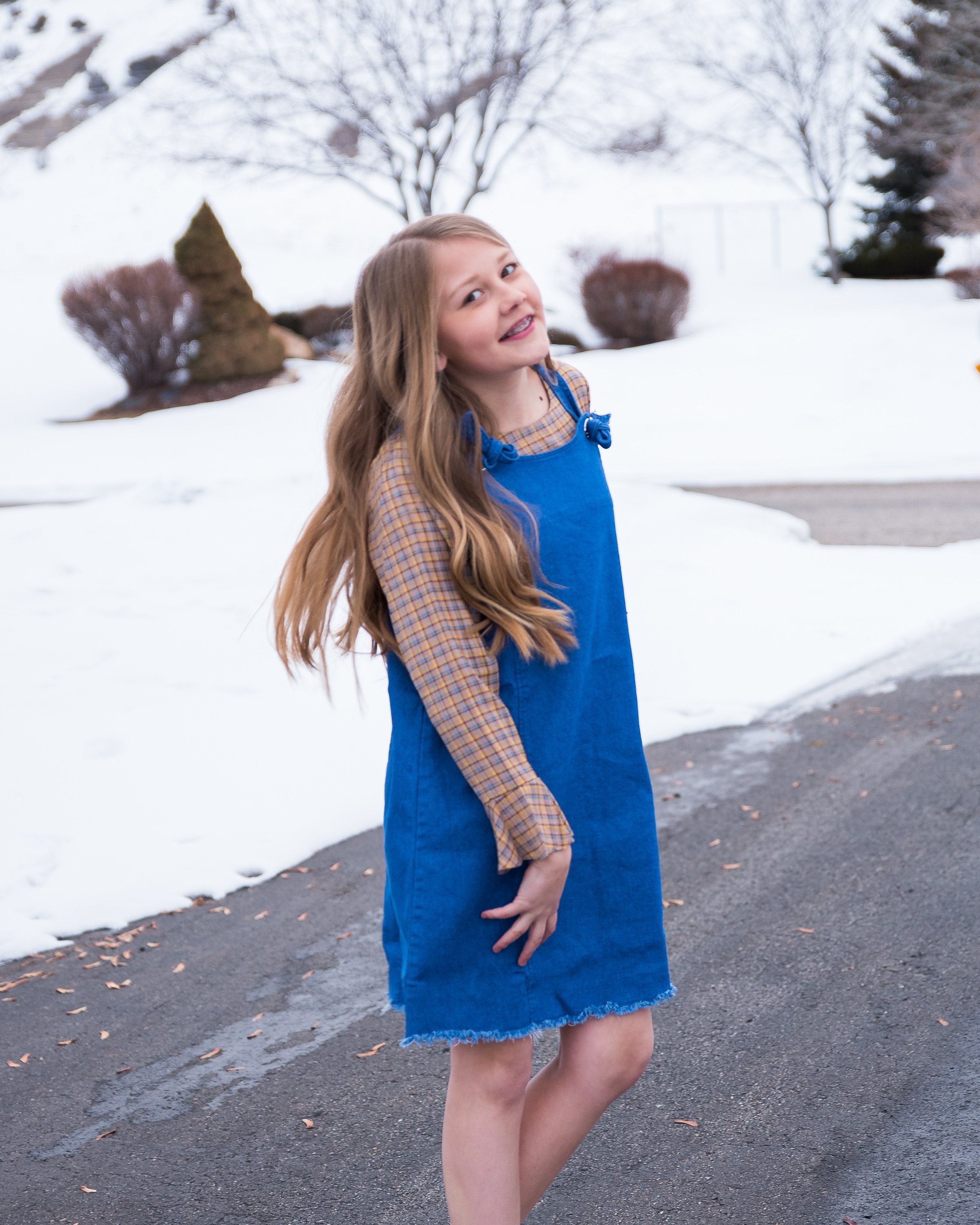 Girls denim overall dress featuring a frayed hem and knotted flower-like straps, perfect for stylish tween outfits.