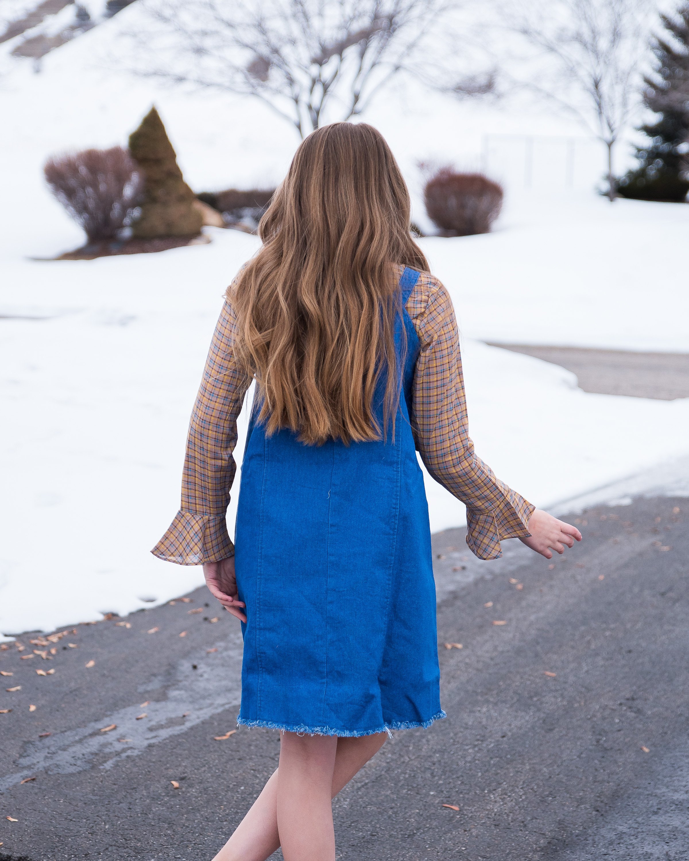 Girls denim overall dress featuring a frayed hem and knotted flower-like straps, perfect for stylish tween outfits.