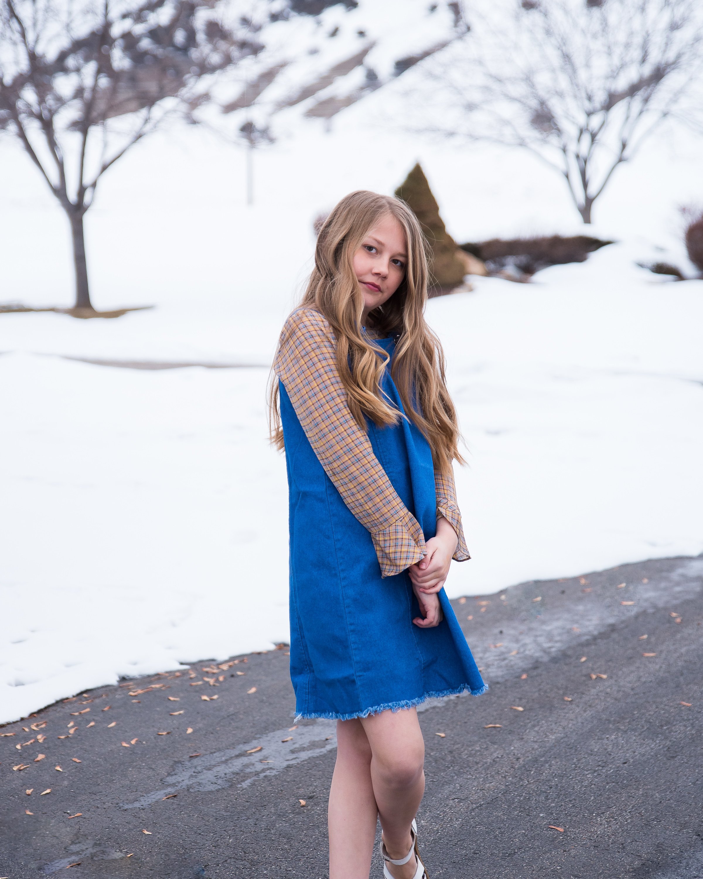 Girls denim overall dress featuring a frayed hem and knotted flower-like straps, perfect for stylish tween outfits.