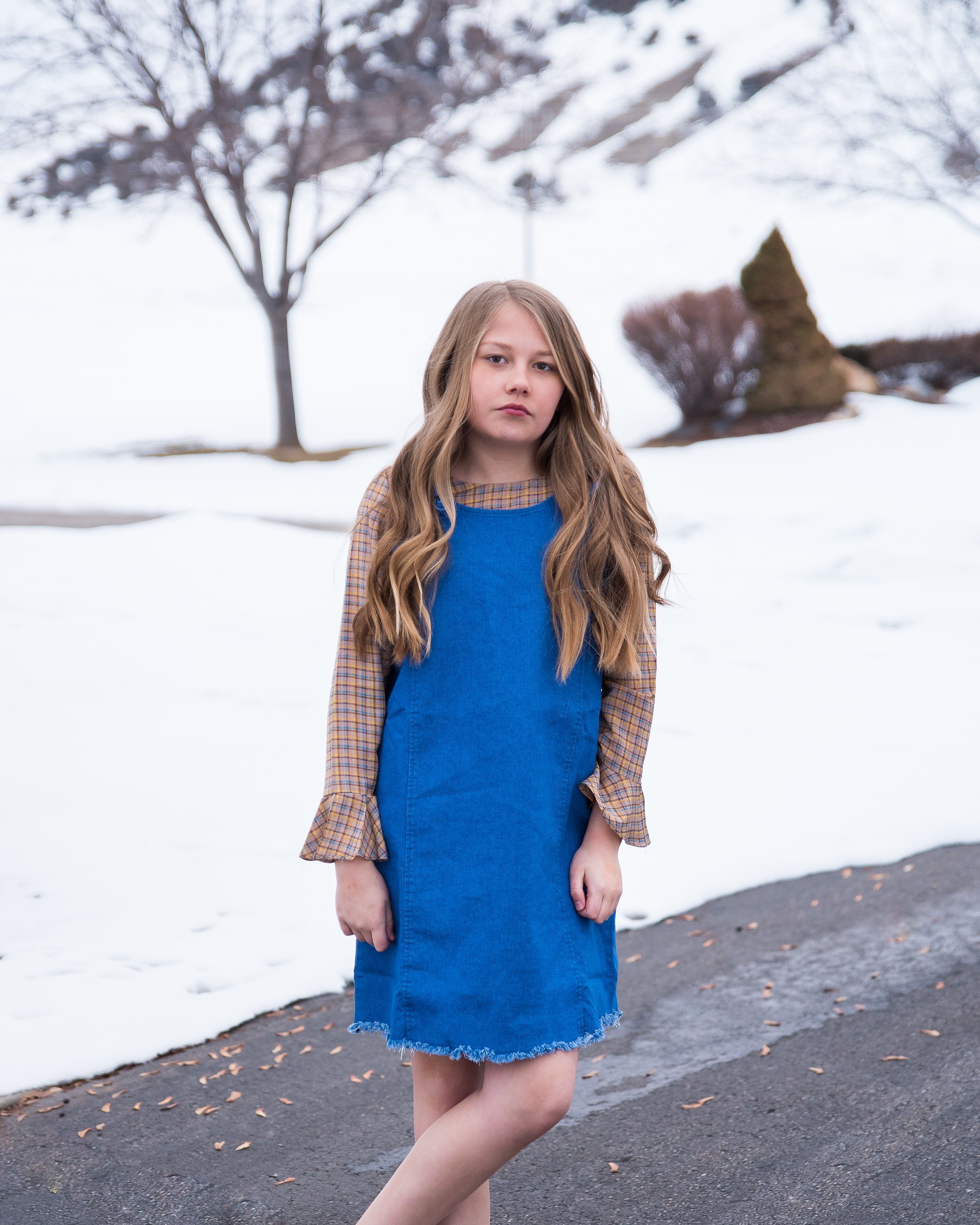 Girls denim overall dress featuring a frayed hem and knotted flower-like straps, perfect for stylish tween outfits.