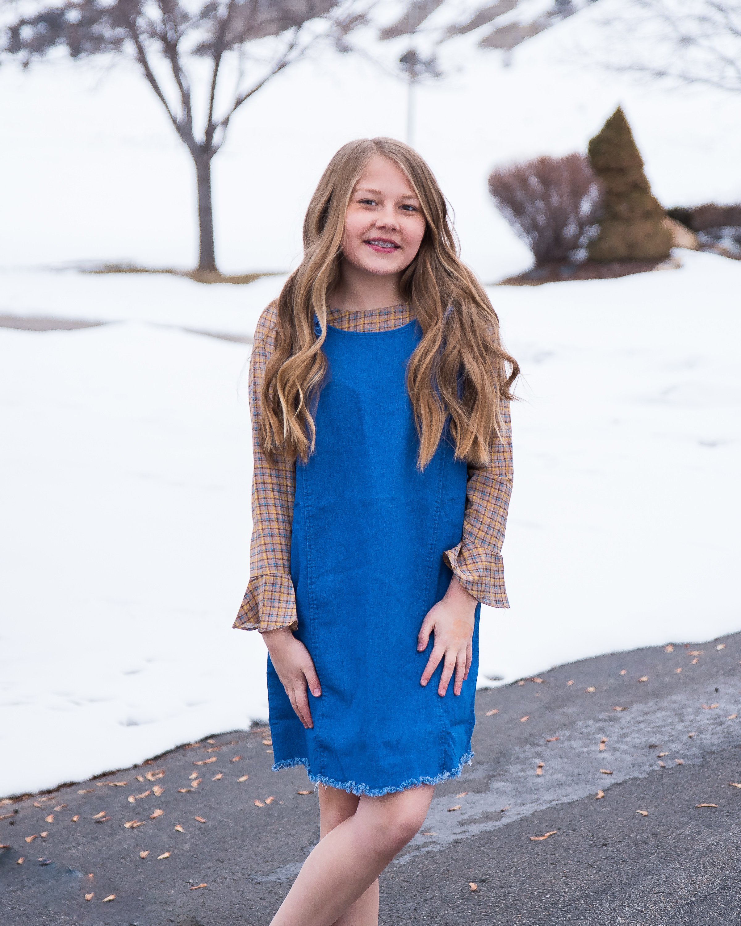 Girls denim overall dress featuring a frayed hem and knotted flower-like straps, perfect for stylish tween outfits.