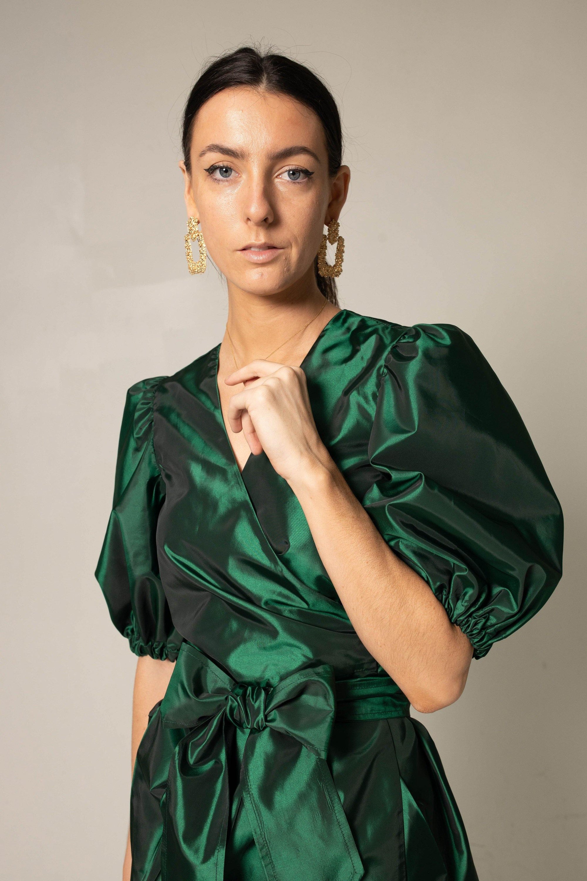 A luxurious green wrap dress from Le Réussi, showcasing its elegant design and plush fabric, perfect for work or cocktail events.