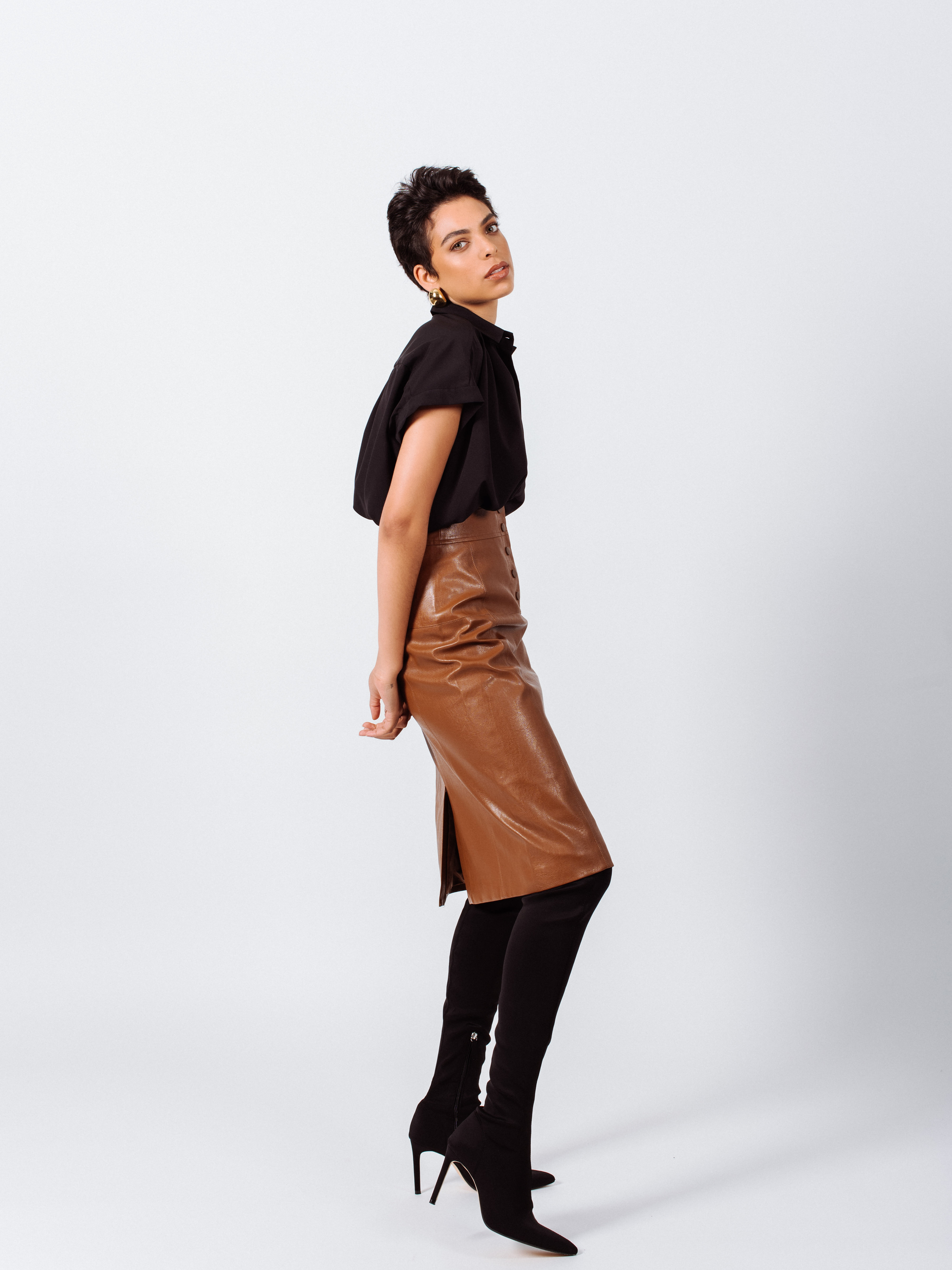 Glossy brown vegan leather pencil skirt with front button detail, knee-length design, and stylish silhouette.