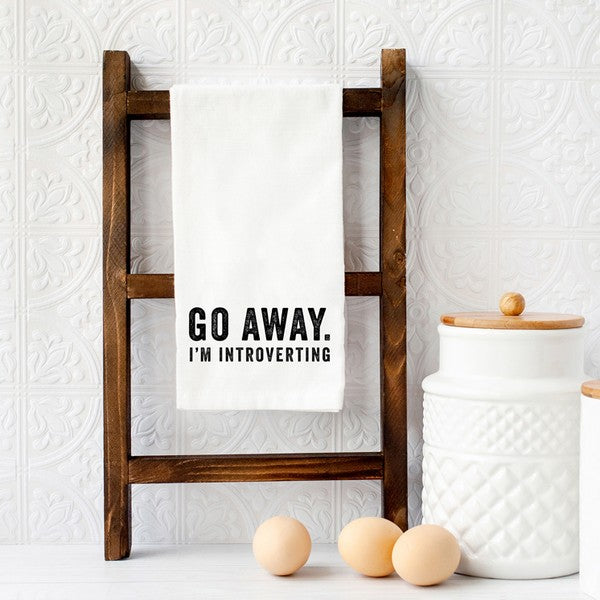 A humorous tea towel with the phrase 'Go Away I'm Introverting' printed on it, showcasing a playful design suitable for introverts.