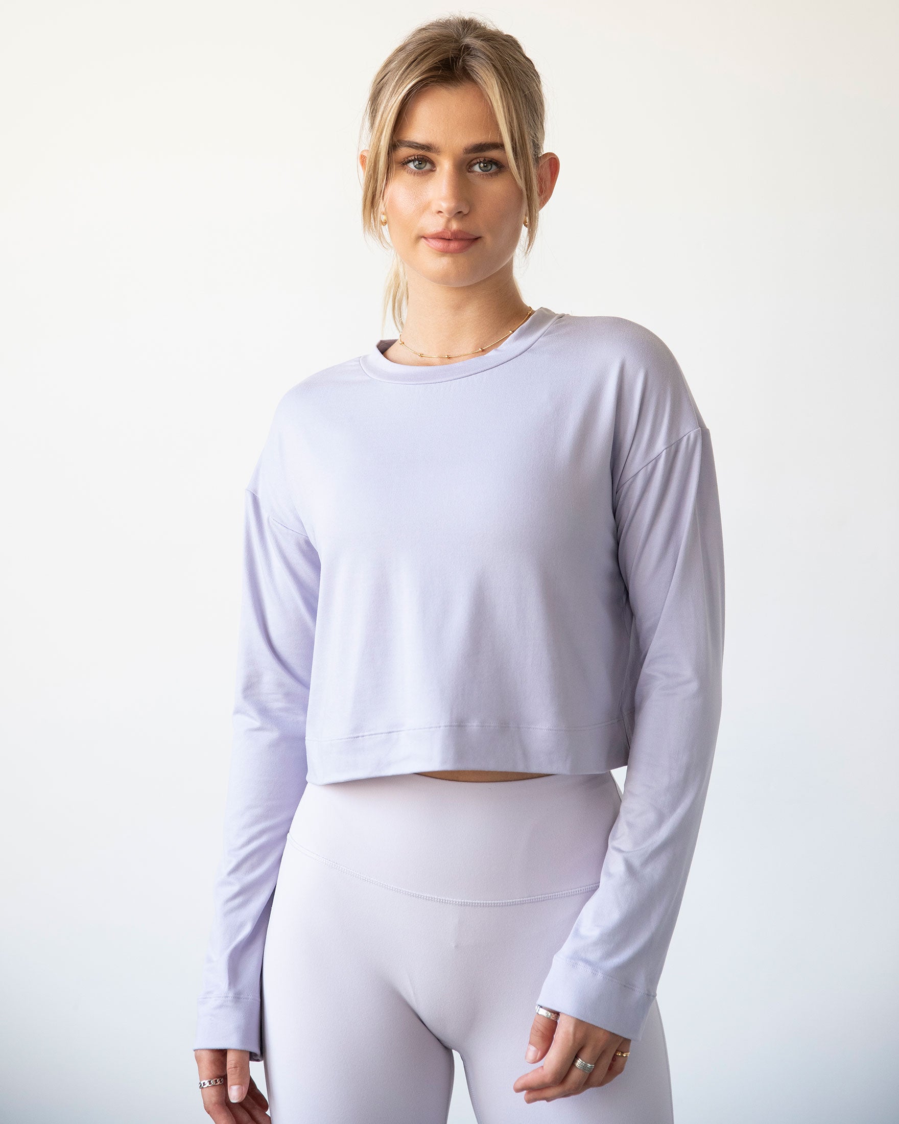 A stylish woman wearing the Go With The Flow Crop Long Sleeve with bell sleeves and a criss-cross back, paired with leggings.