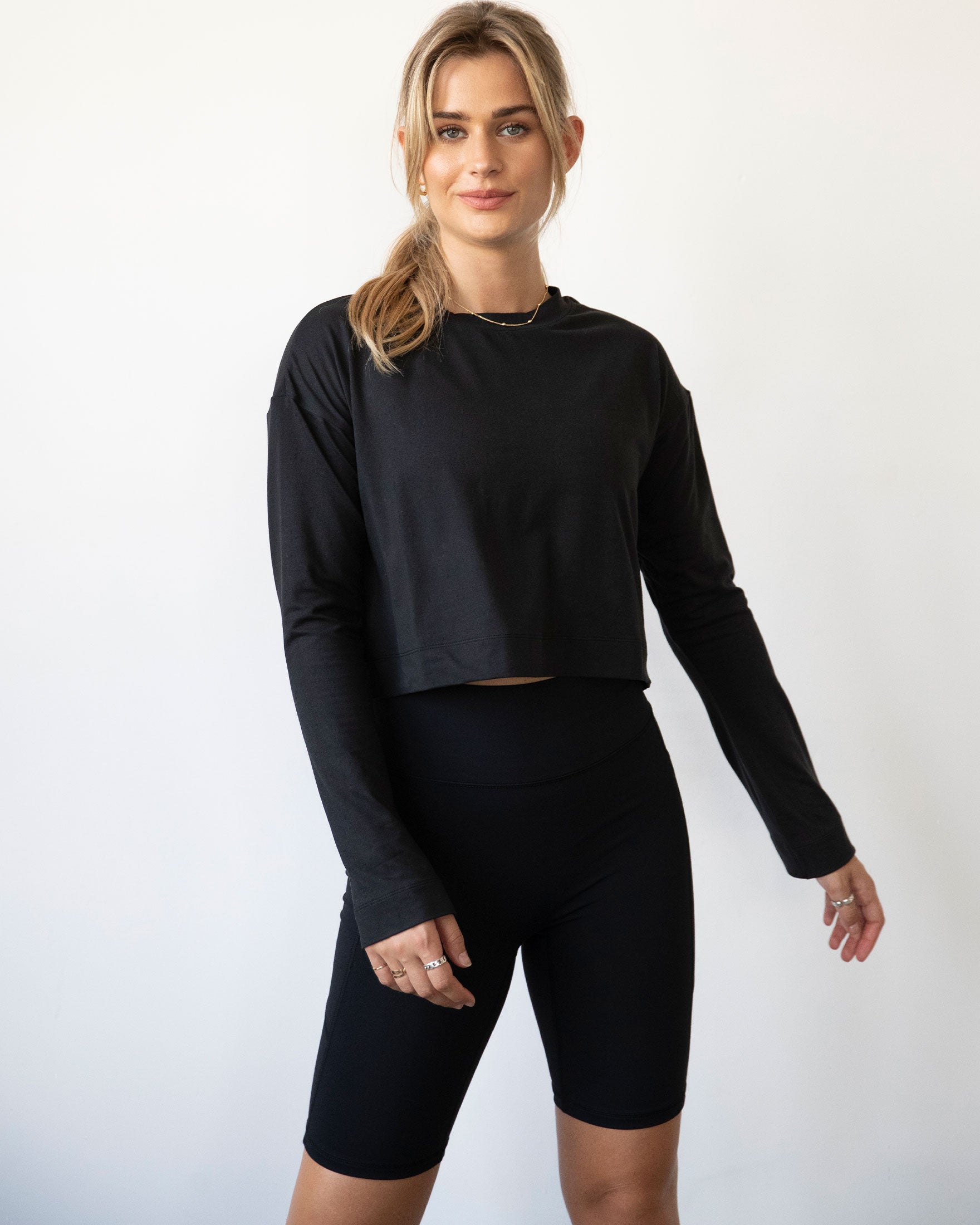 A stylish woman wearing the Go With The Flow Crop Long Sleeve with bell sleeves and a criss-cross back, paired with leggings.