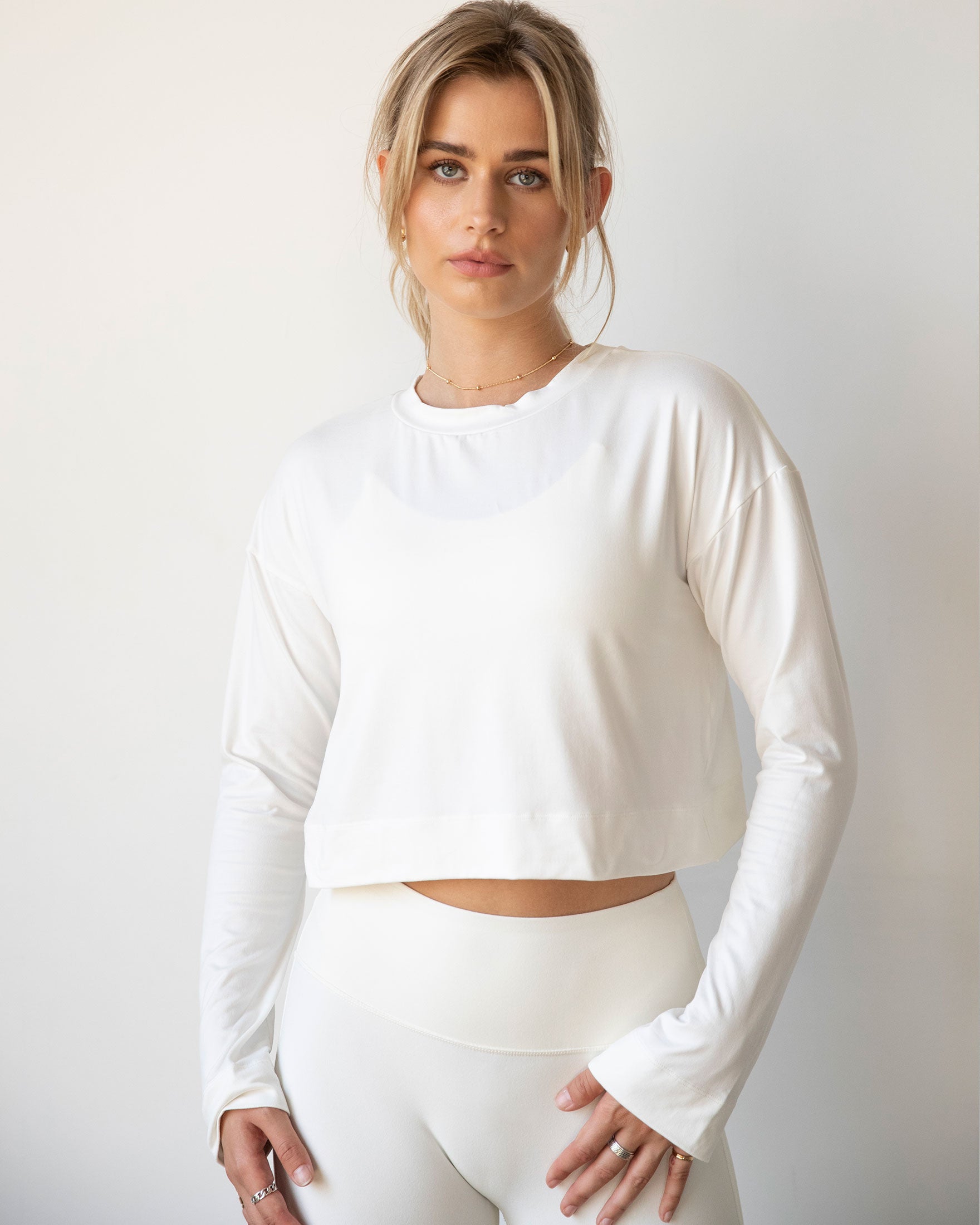 A stylish woman wearing the Go With The Flow Crop Long Sleeve with bell sleeves and a criss-cross back, paired with leggings.