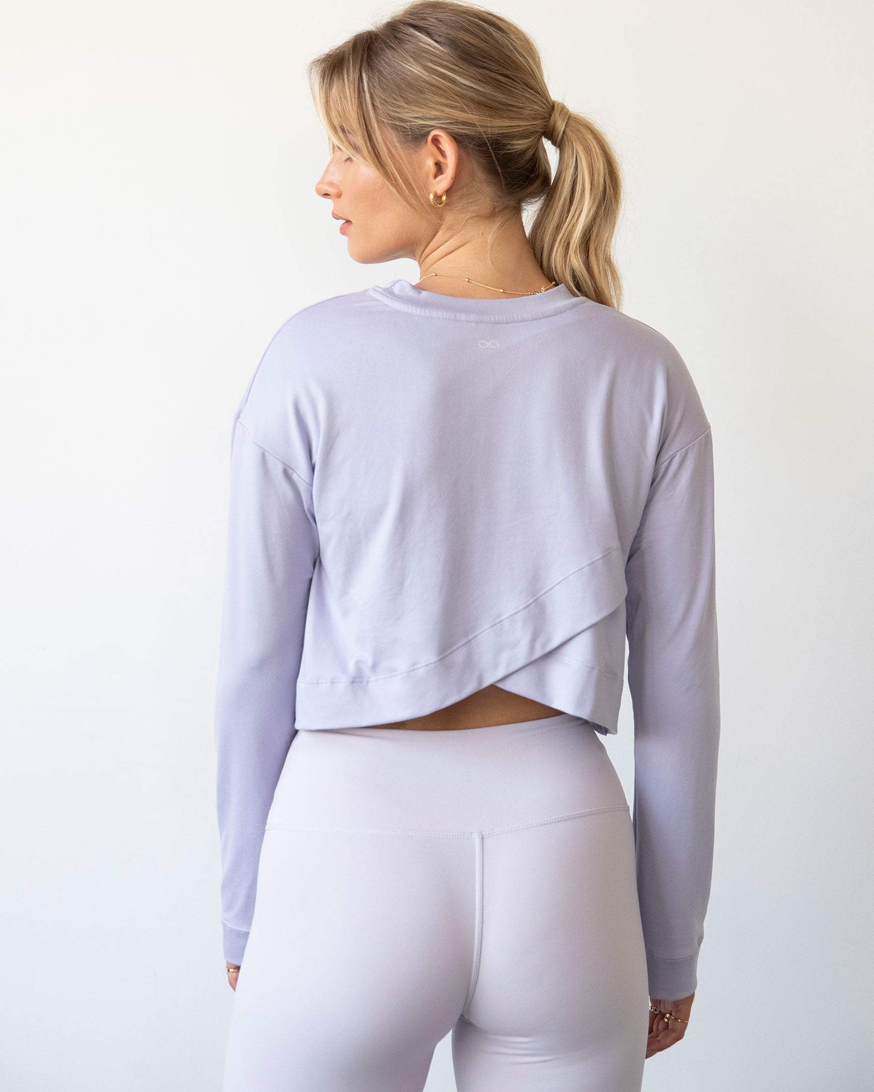 A stylish woman wearing the Go With The Flow Crop Long Sleeve with bell sleeves and a criss-cross back, paired with leggings.