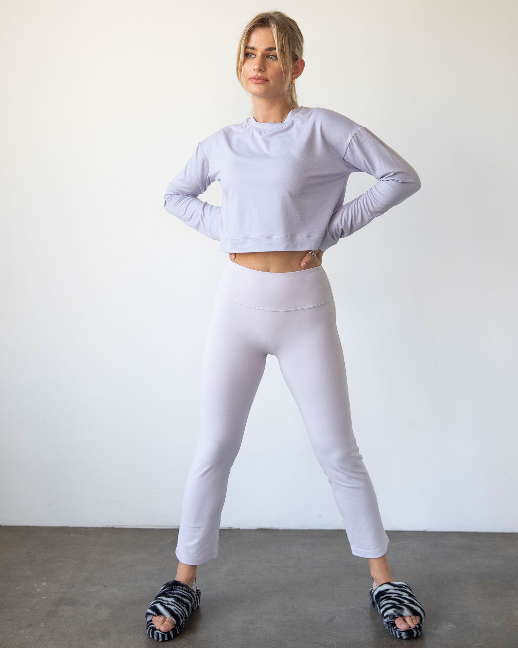 A stylish woman wearing the Go With The Flow Crop Long Sleeve with bell sleeves and a criss-cross back, paired with leggings.