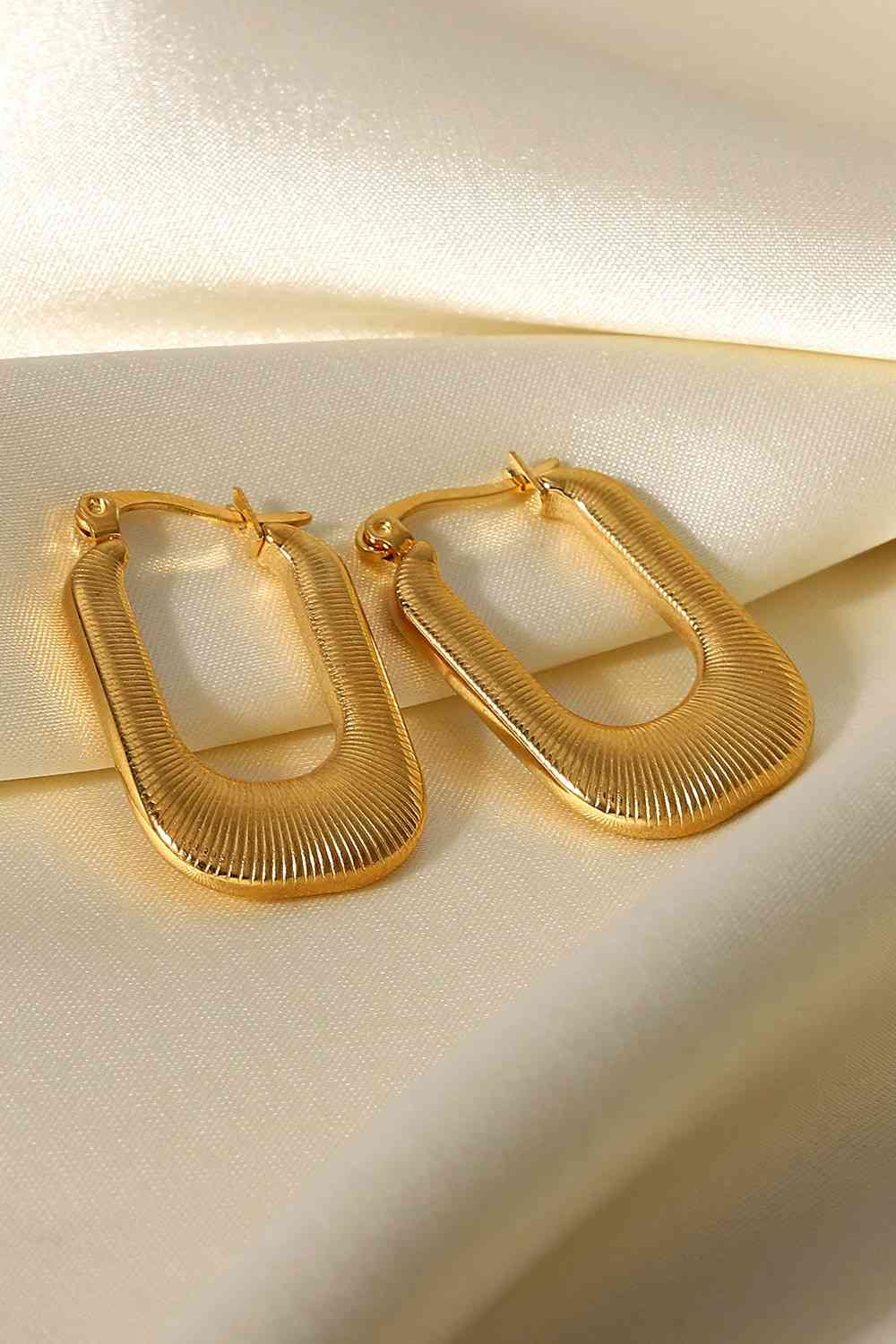 A pair of gold-plated stainless steel U-shaped earrings with a screw-thread texture, showcasing a chunky and sophisticated design.