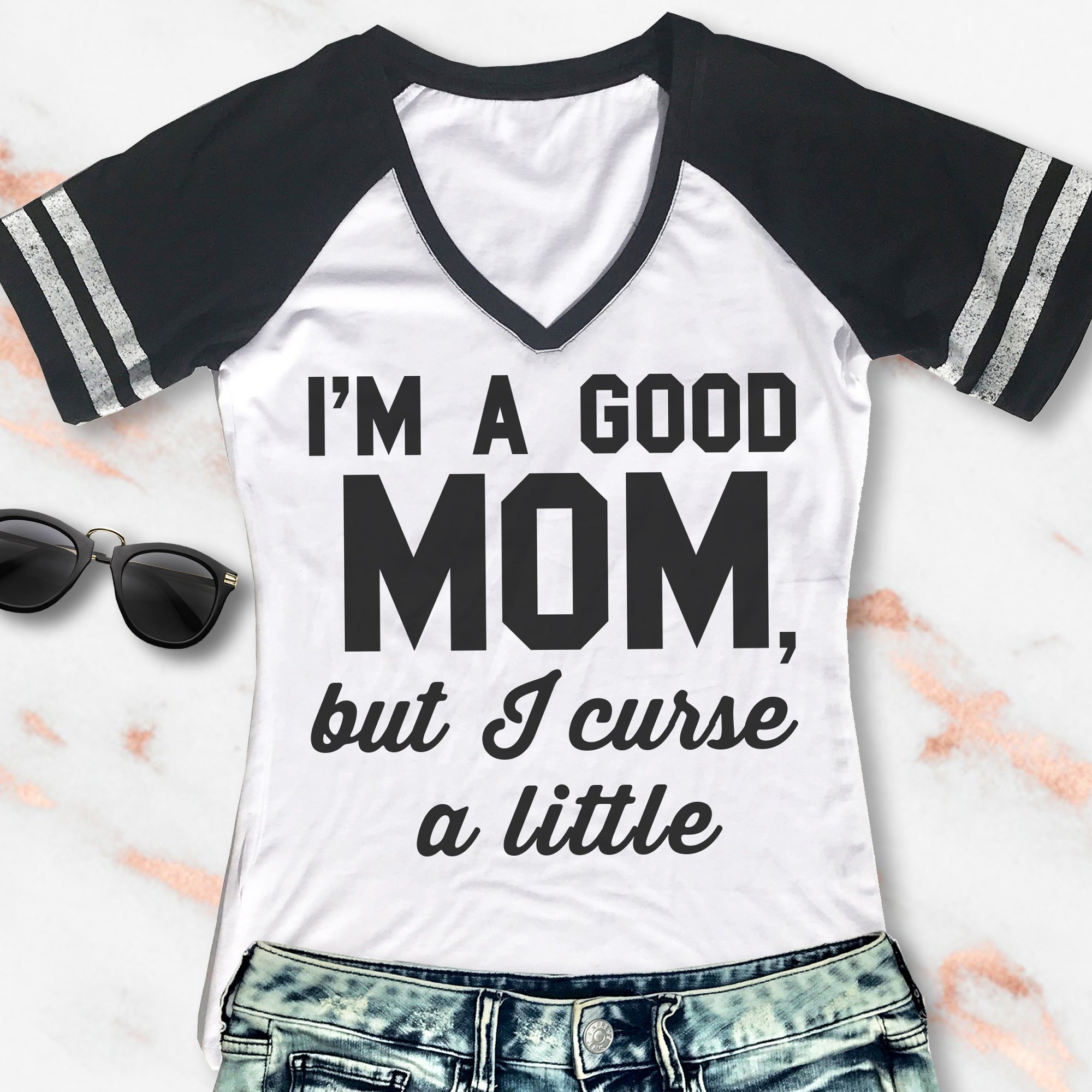 A stylish women's V-neck shirt featuring the phrase 'I'm a Good Mom, but I curse a little', available in black with gray sleeves and white with black sleeves.