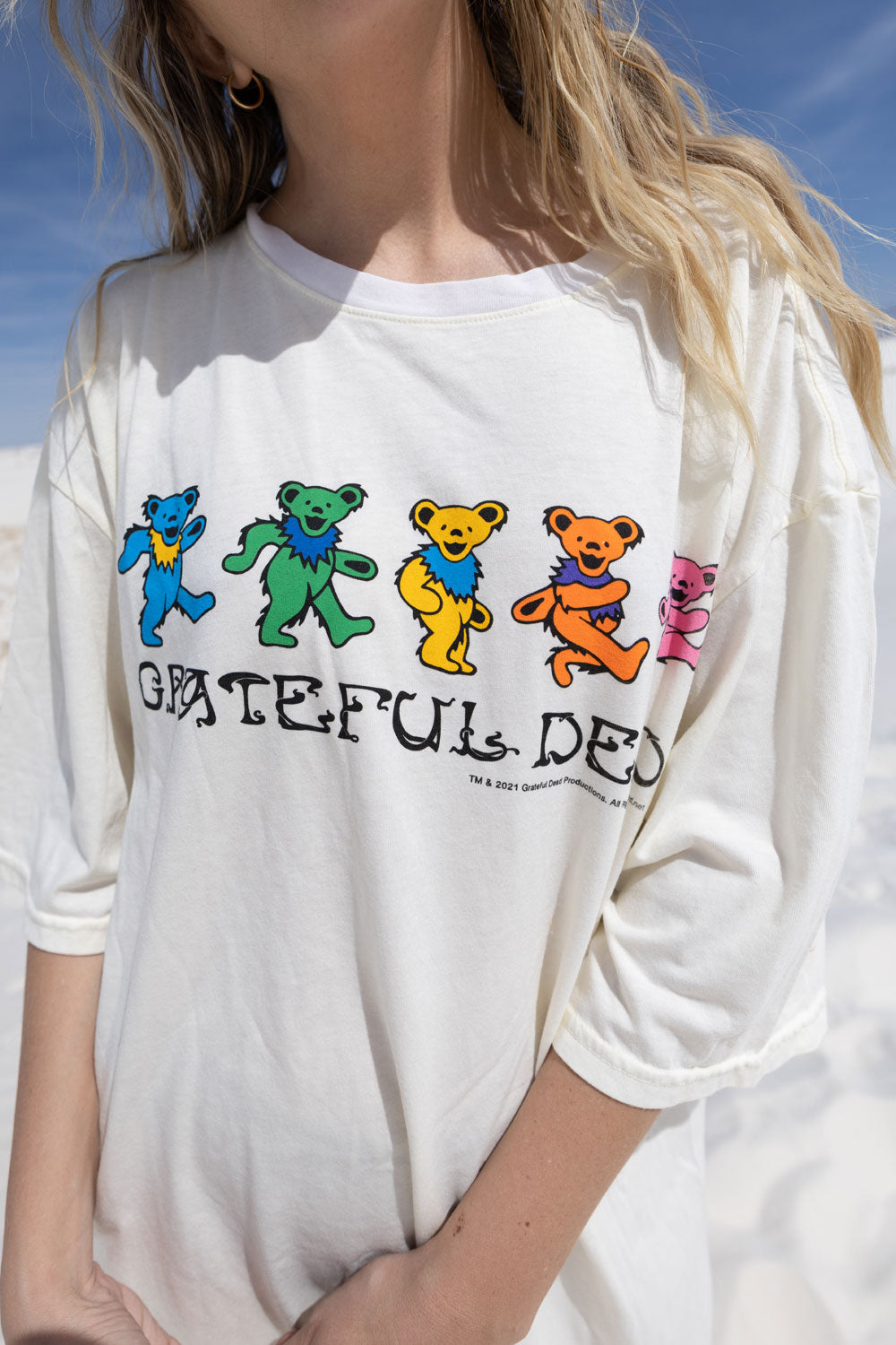 A vibrant Grateful Dead Tee Dress featuring a colorful tie-dye print, knee length, crew neck, and side slit, showcasing the iconic Grateful Dead Bear graphic.