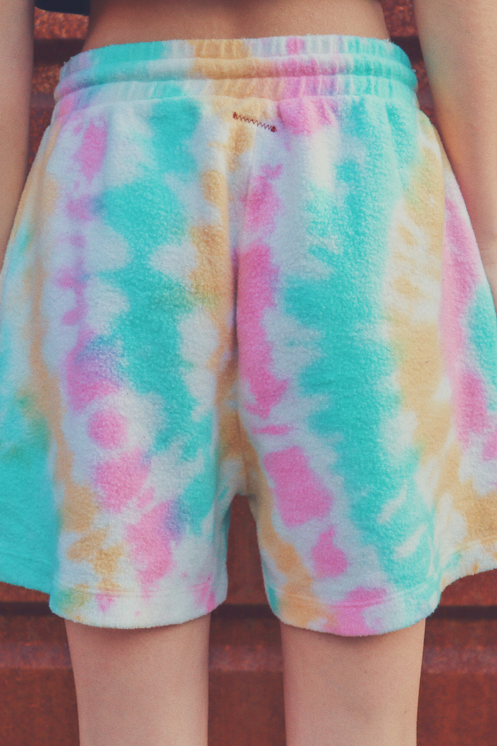 A pair of vibrant tie-dye shorts in Malibu and Miami colors, made from eco-friendly plush fleece fabric, featuring a drawstring waist and trouser pockets.