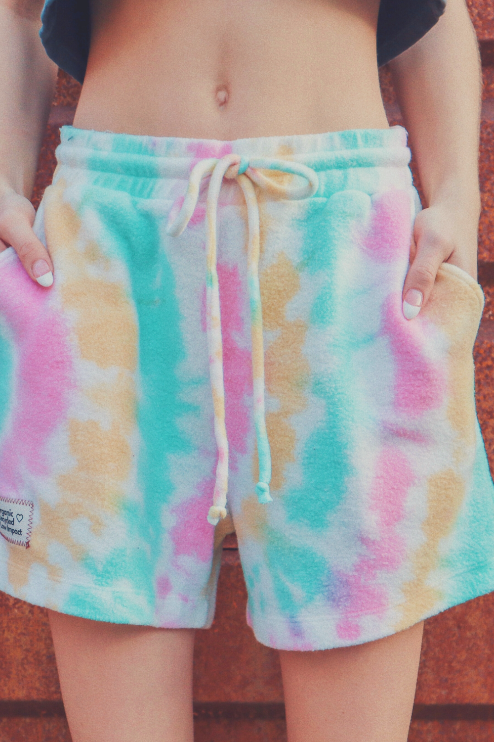 A pair of vibrant tie-dye shorts in Malibu and Miami colors, made from eco-friendly plush fleece fabric, featuring a drawstring waist and trouser pockets.