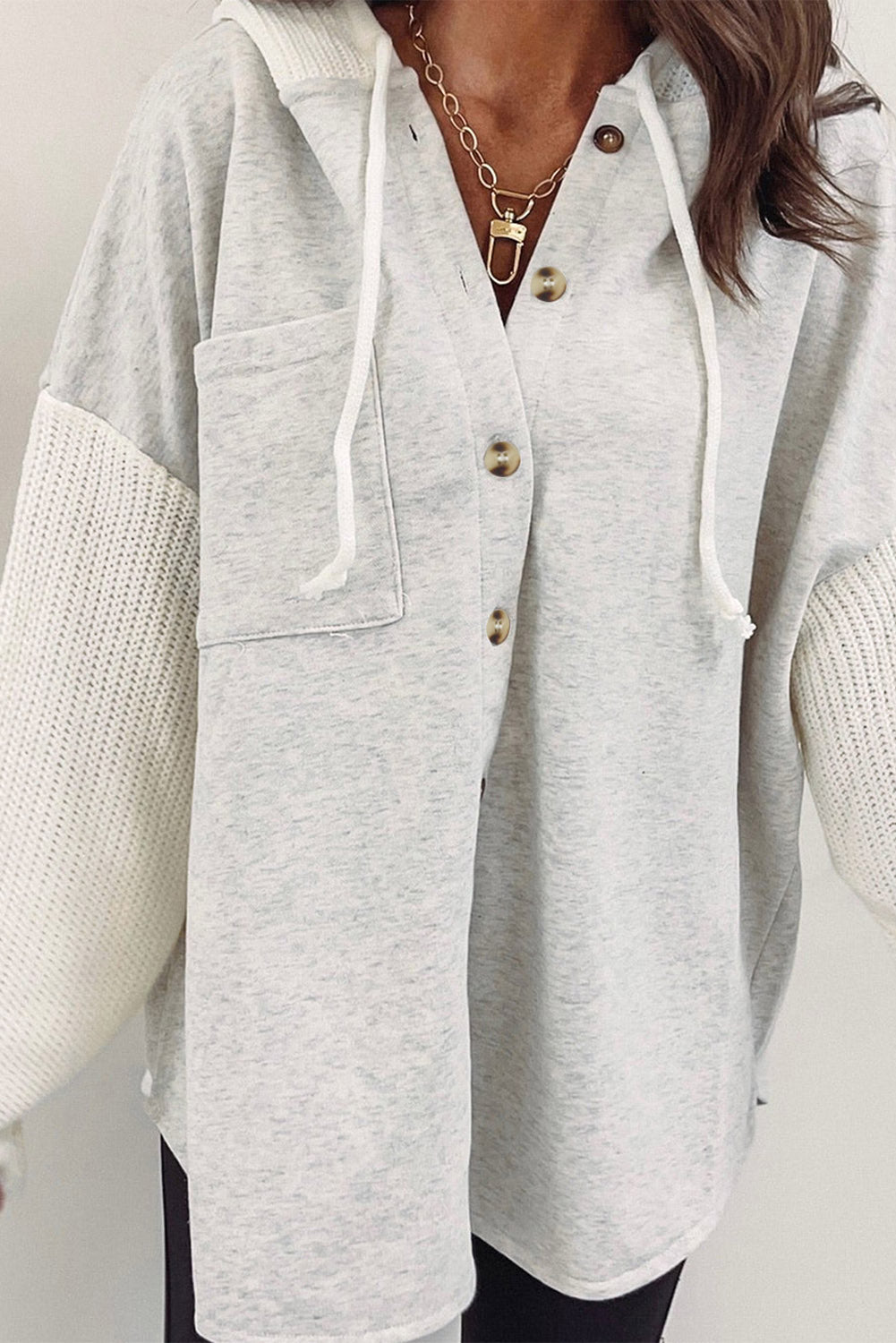 Gray button-up hooded jacket with contrast knitted sleeves, showcasing a stylish and cozy design.