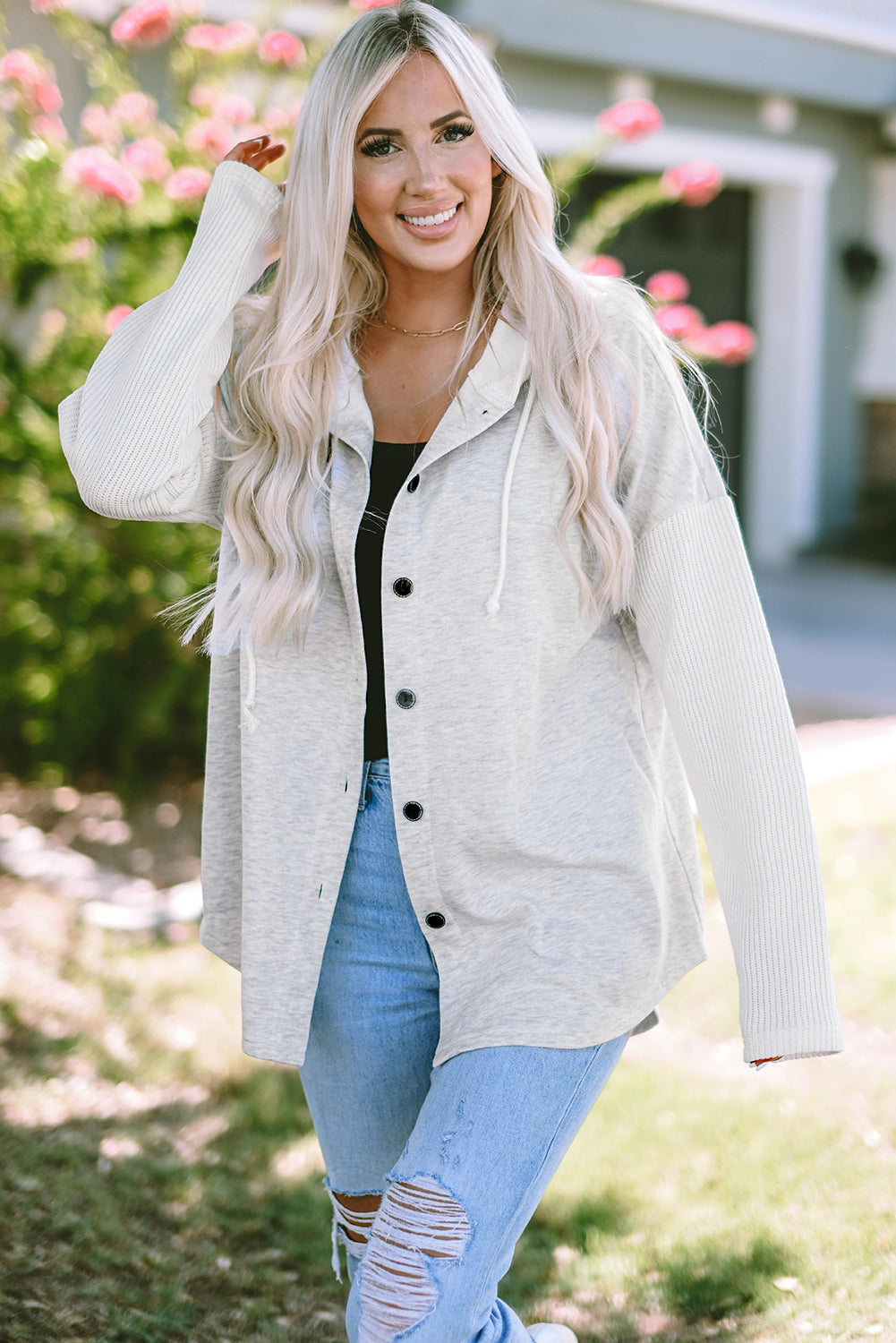 Gray button-up hooded jacket with contrast knitted sleeves, showcasing a stylish and cozy design.