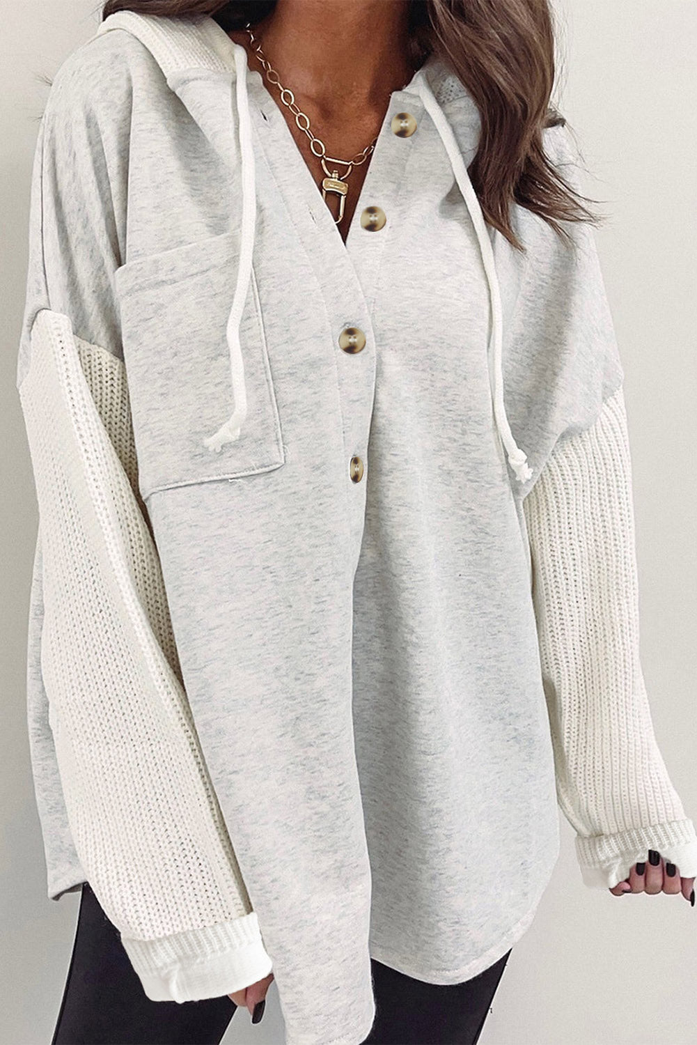 Gray button-up hooded jacket with contrast knitted sleeves, showcasing a stylish and cozy design.