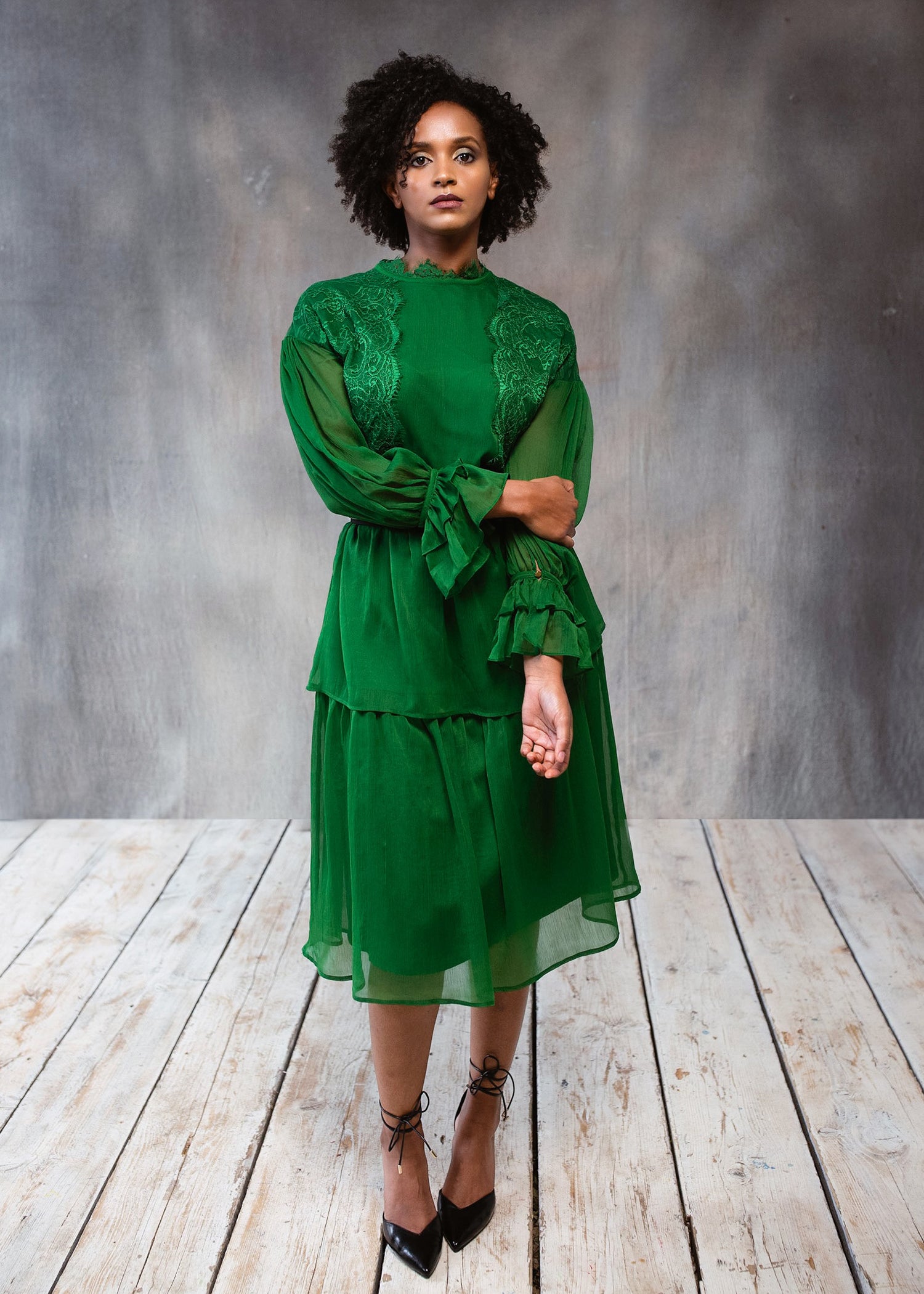 A beautiful green lace dress with long sleeves and a tiered design, perfect for elegant occasions.