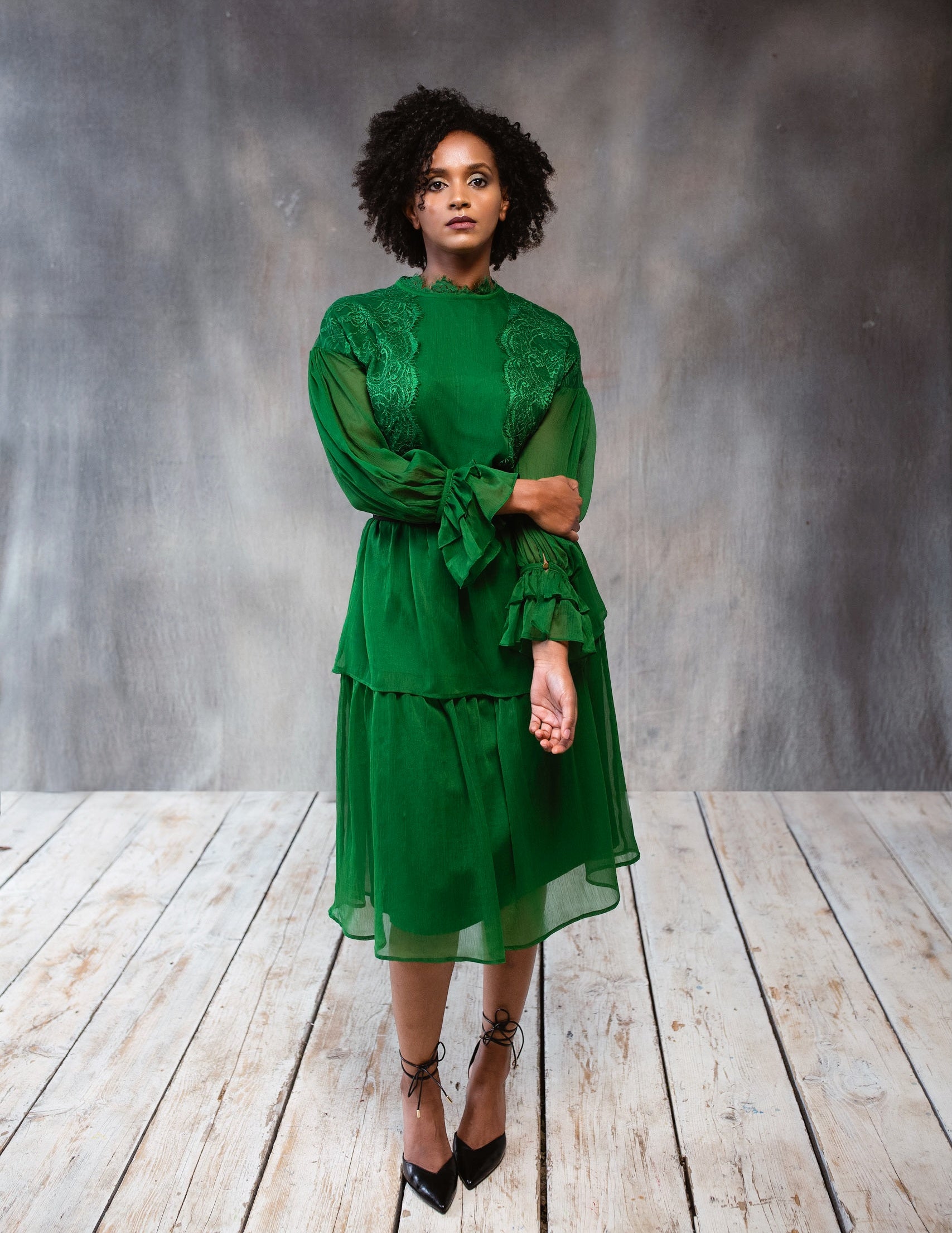 A beautiful green lace dress with long sleeves and a tiered design, perfect for elegant occasions.