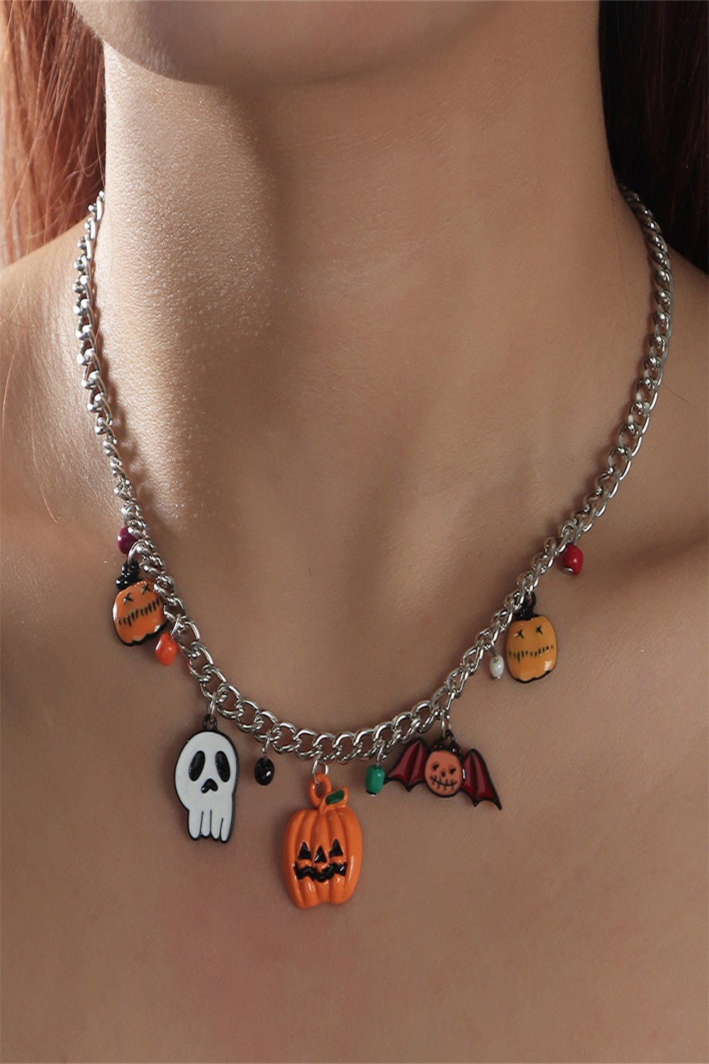 A Halloween charm bracelet and necklace set featuring pumpkin and ghost charms, made from alloy and resin, displayed on a festive background.