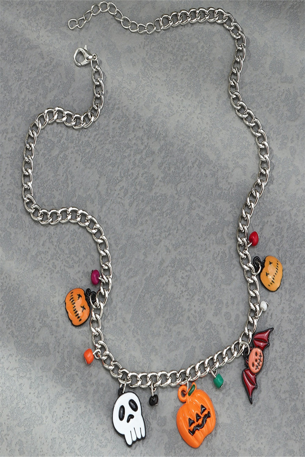 A Halloween charm bracelet and necklace set featuring pumpkin and ghost charms, made from alloy and resin, displayed on a festive background.