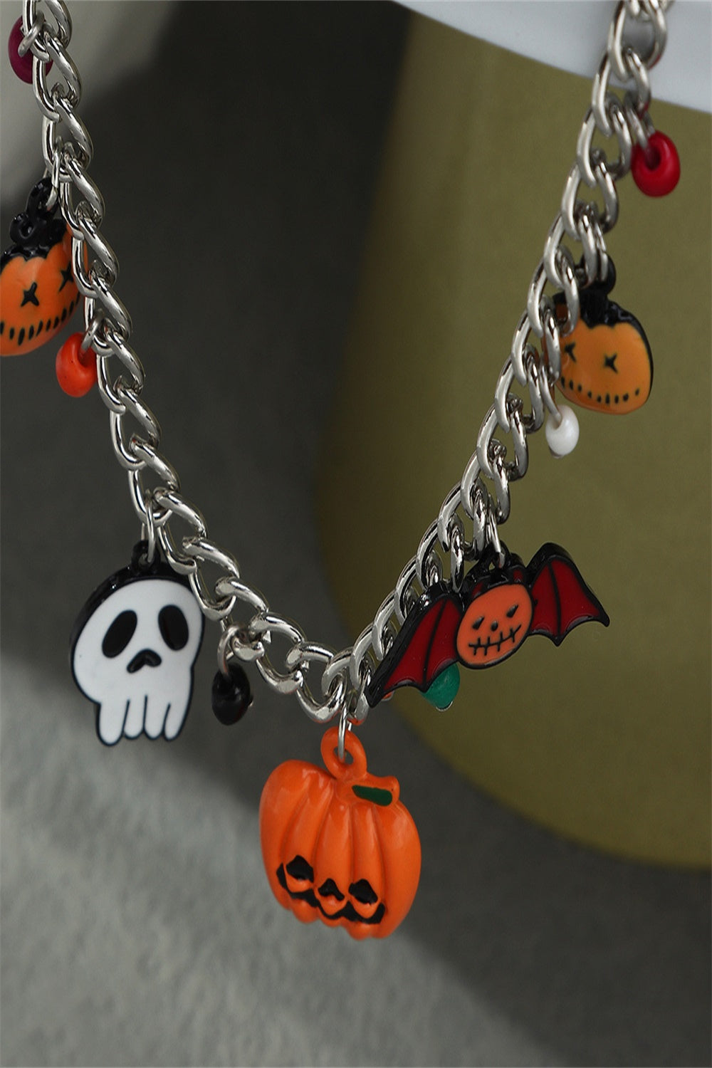 A Halloween charm bracelet and necklace set featuring pumpkin and ghost charms, made from alloy and resin, displayed on a festive background.