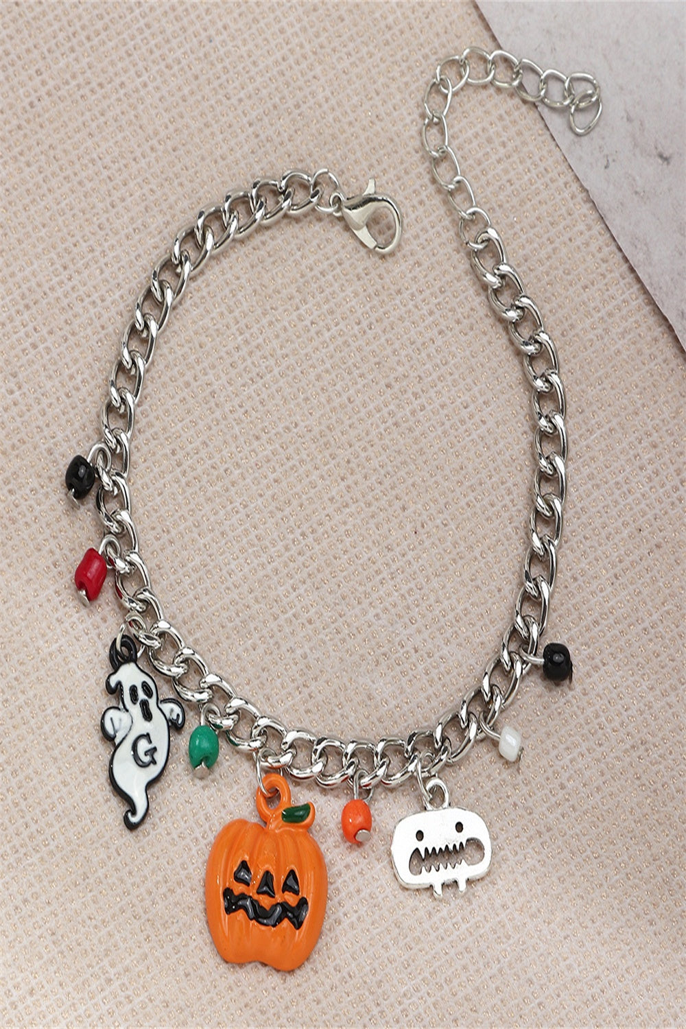 A Halloween charm bracelet and necklace set featuring pumpkin and ghost charms, made from alloy and resin, displayed on a festive background.