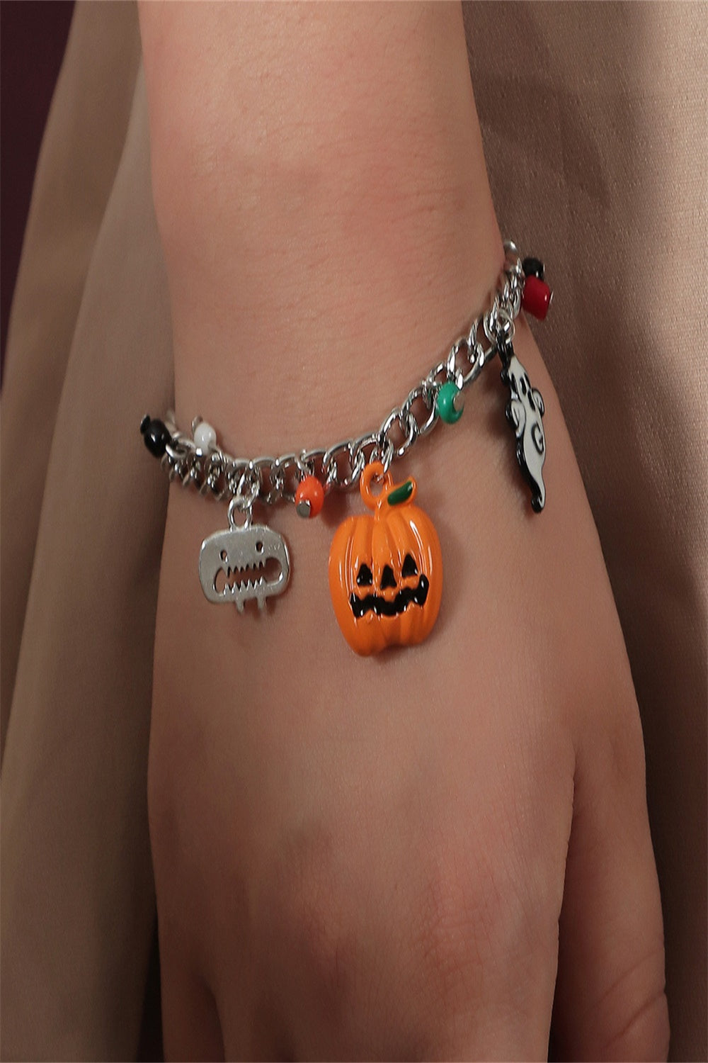 A Halloween charm bracelet and necklace set featuring pumpkin and ghost charms, made from alloy and resin, displayed on a festive background.