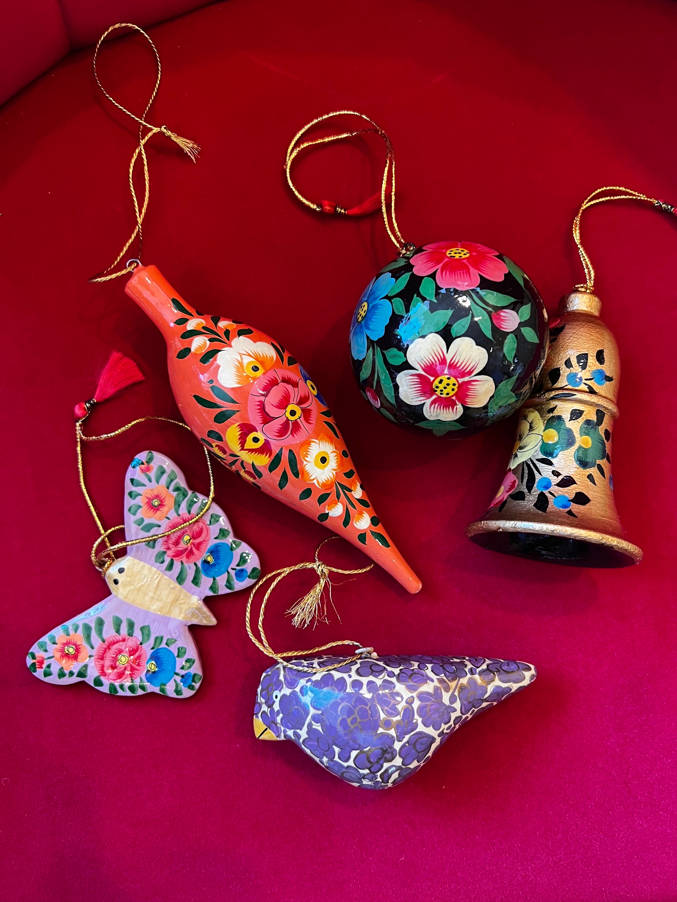 A collection of vibrant hand-painted papier mâché holiday ornaments in assorted colors and designs, showcasing intricate craftsmanship.