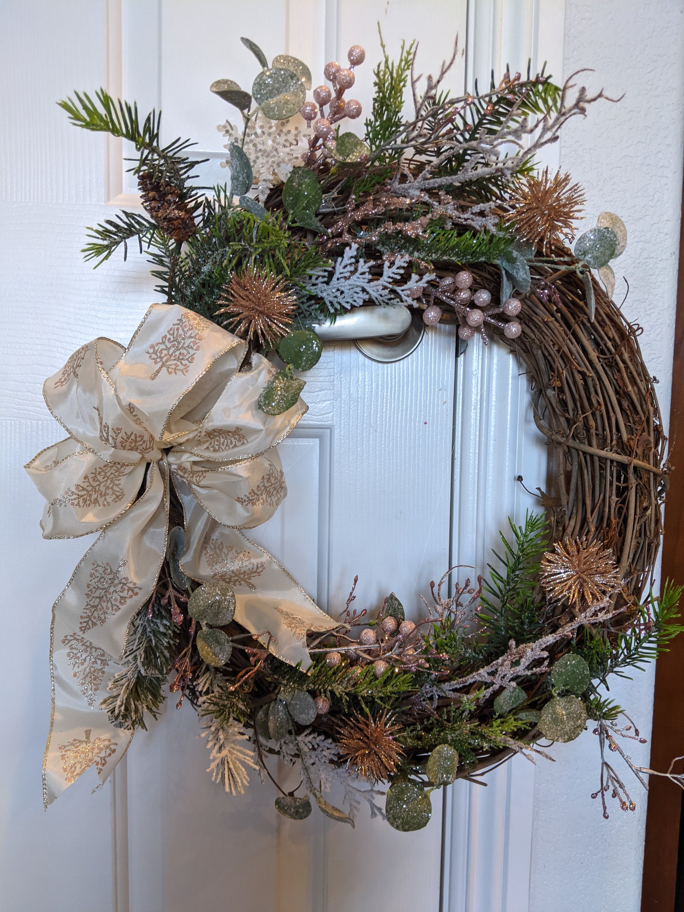 Handmade 18-inch grapevine wreath featuring sugary pink shades and winter greens, perfect for seasonal decor.