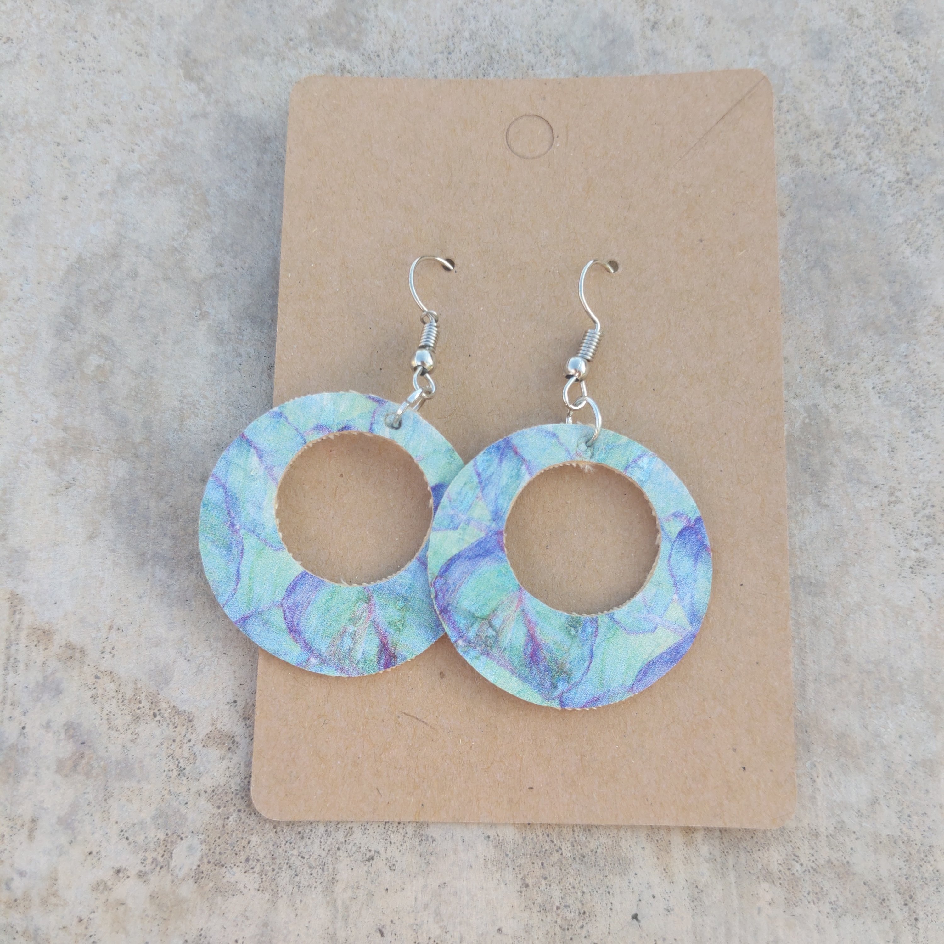 A pair of handmade blue tie dye cork earrings, showcasing a vibrant and unique design, lightweight and perfect for any outfit.