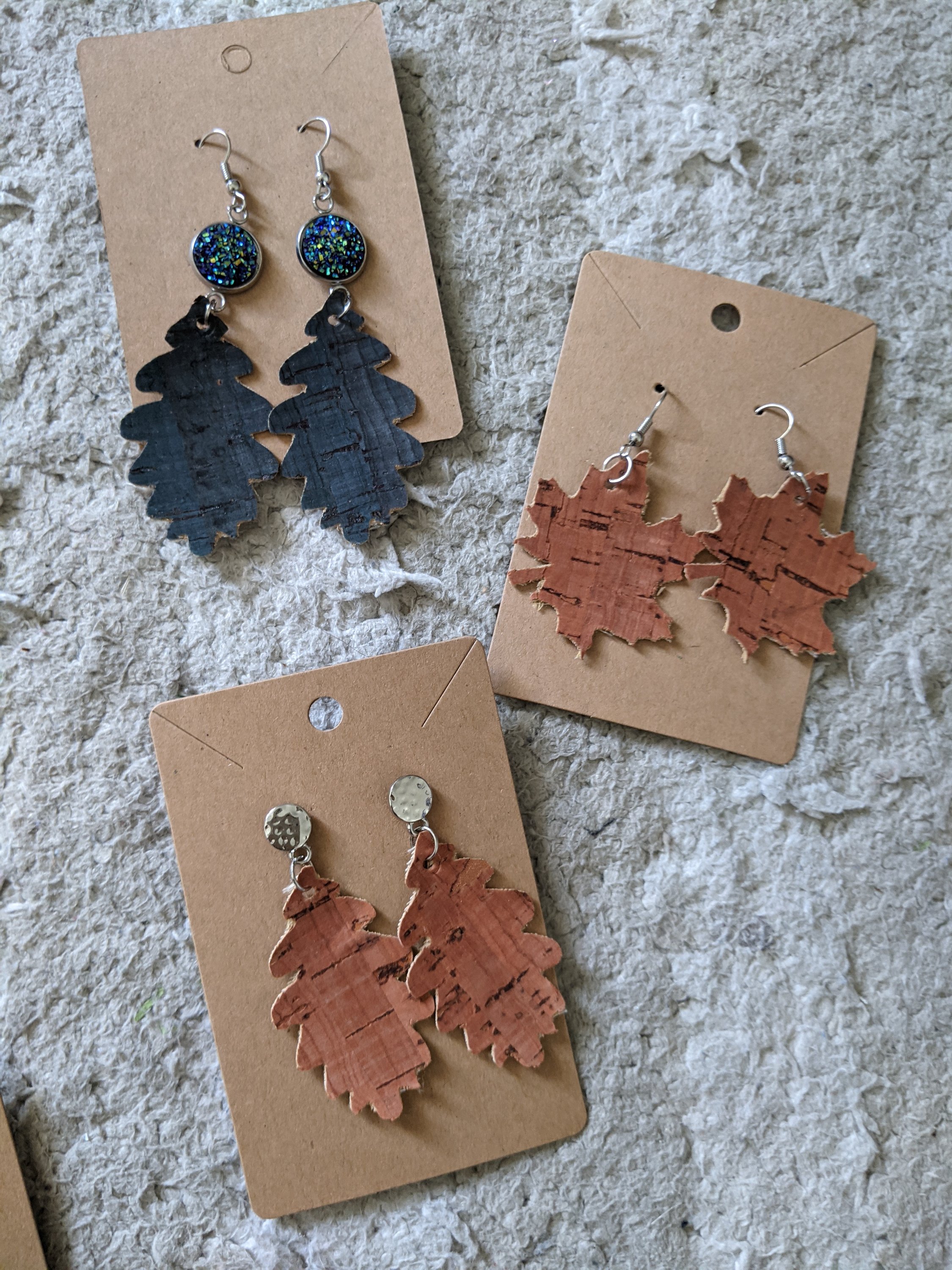 A pair of handmade cork earrings shaped like fall leaves, showcasing intricate details and a natural finish, perfect for autumn fashion.