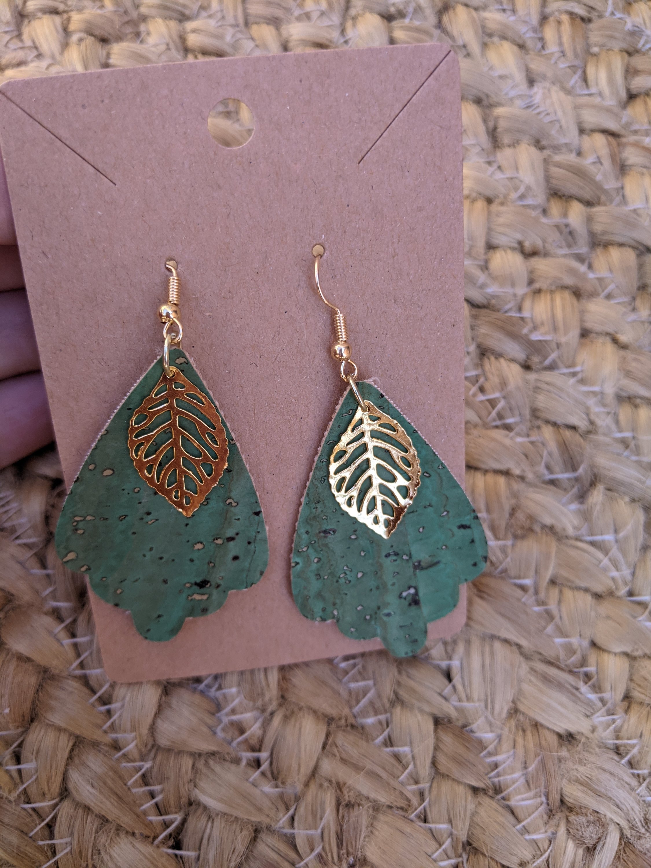 Handmade light green cork earrings featuring a delicate leaf filigree charm, showcasing their unique design and lightweight nature.