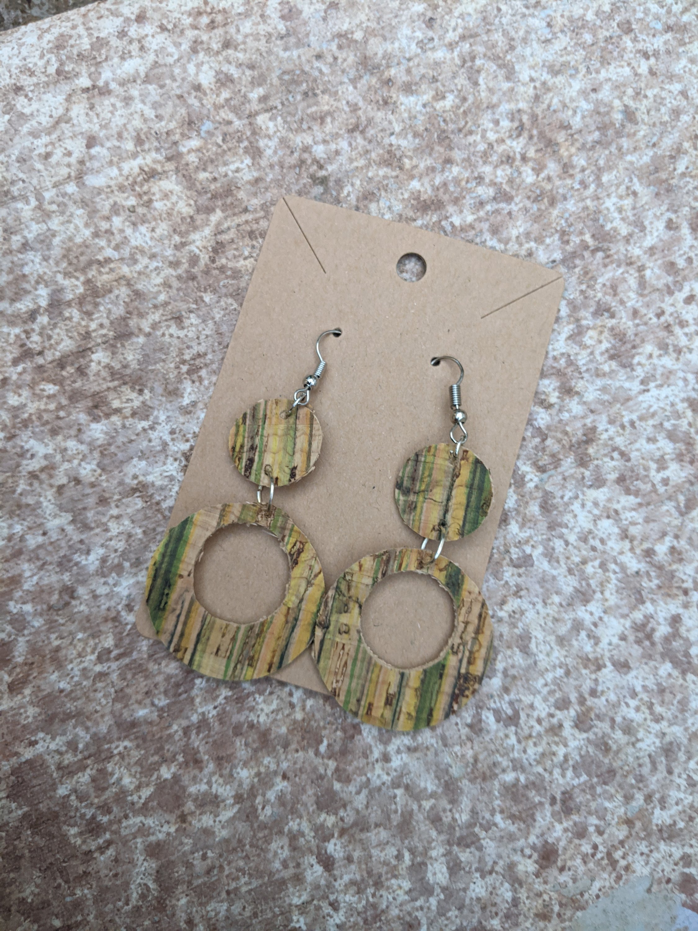 Handmade light green cork earrings featuring a delicate leaf filigree charm, showcasing their unique design and lightweight nature.